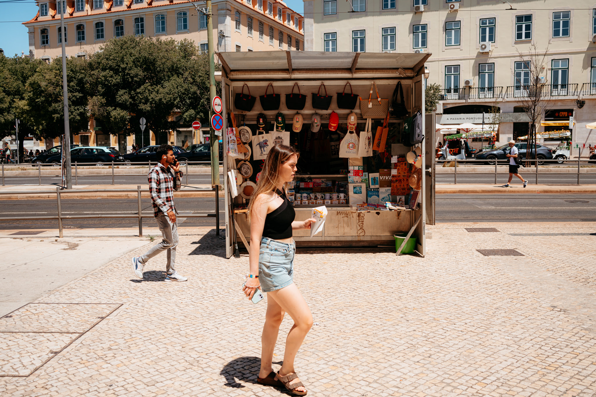 Woman walking past a tourist kiosk in Lisbon.