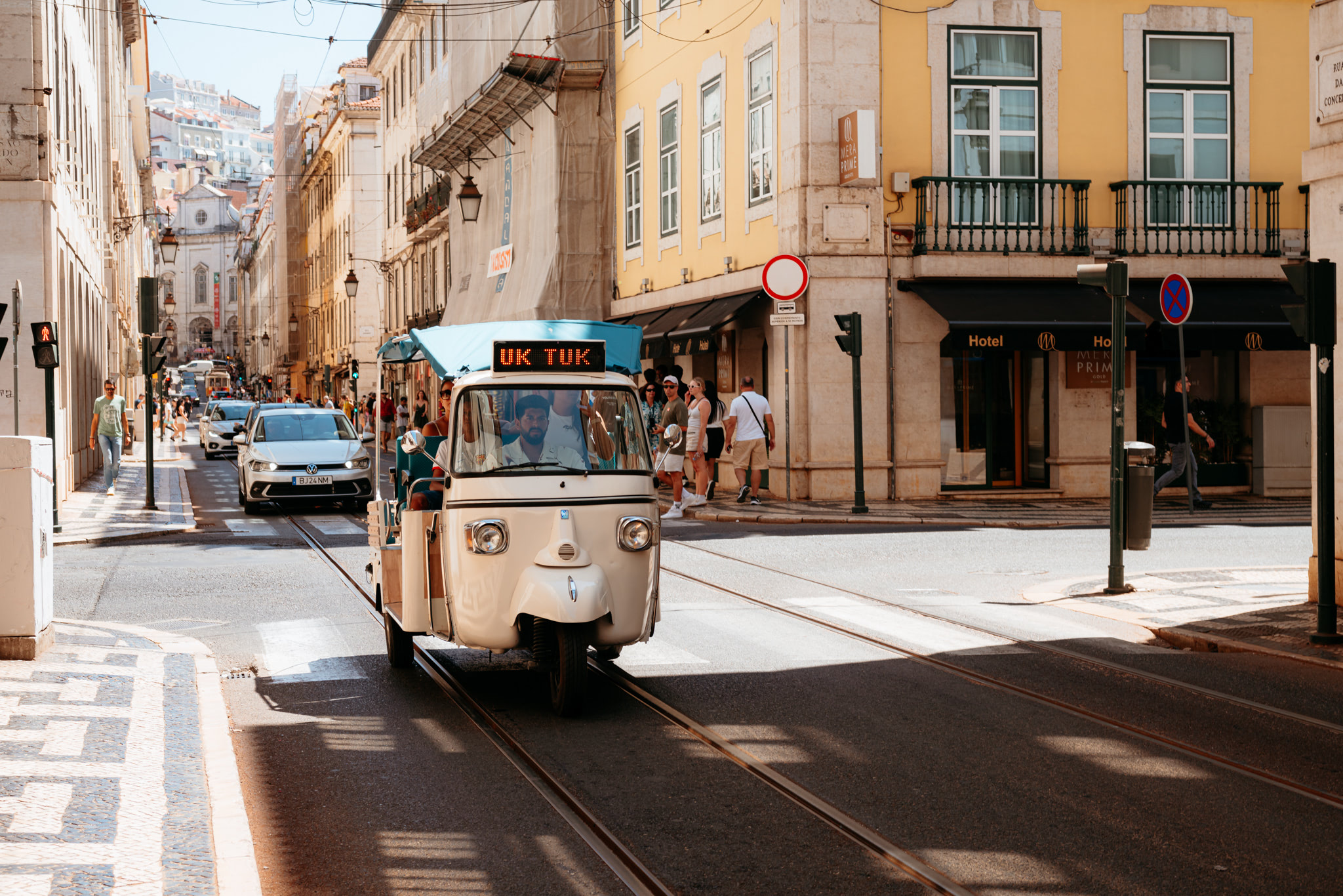 Tuk-tuk driving down a Lisbon street.