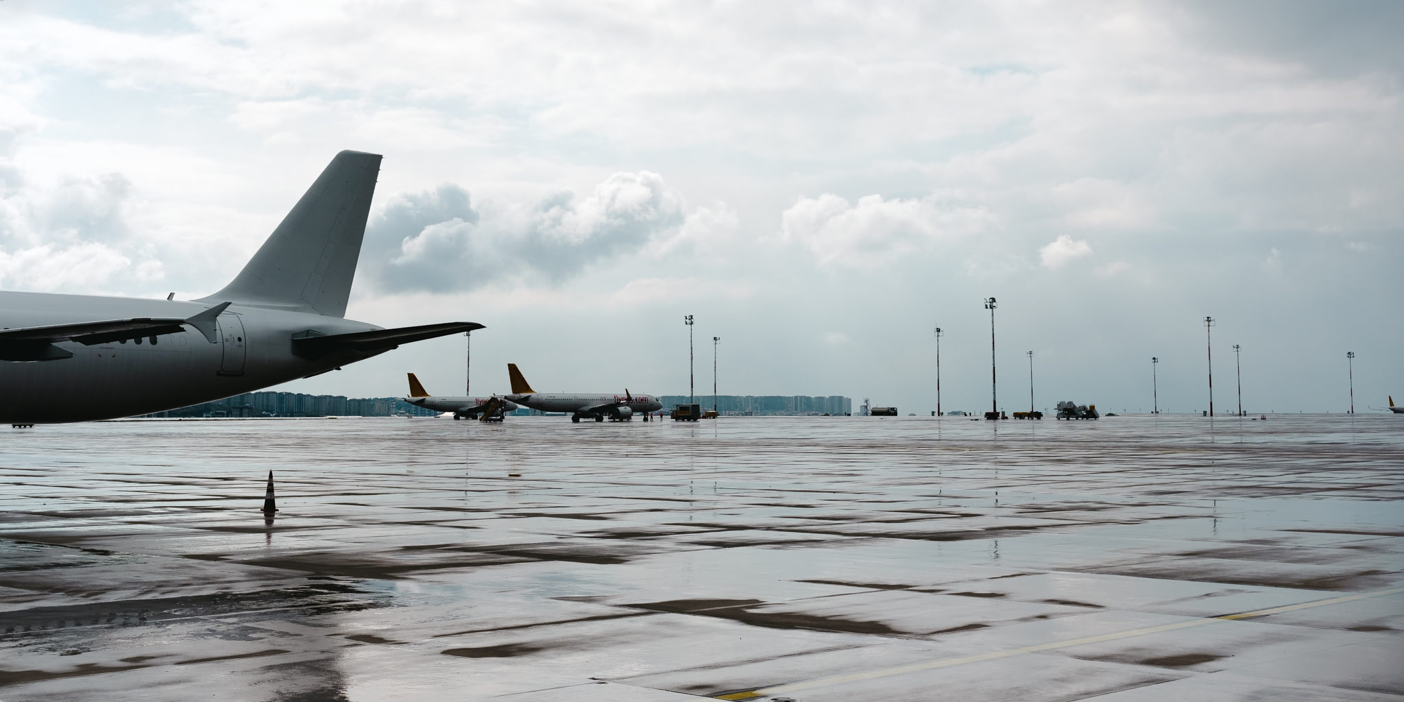Airplanes on wet airport tarmac under a cloudy sky.