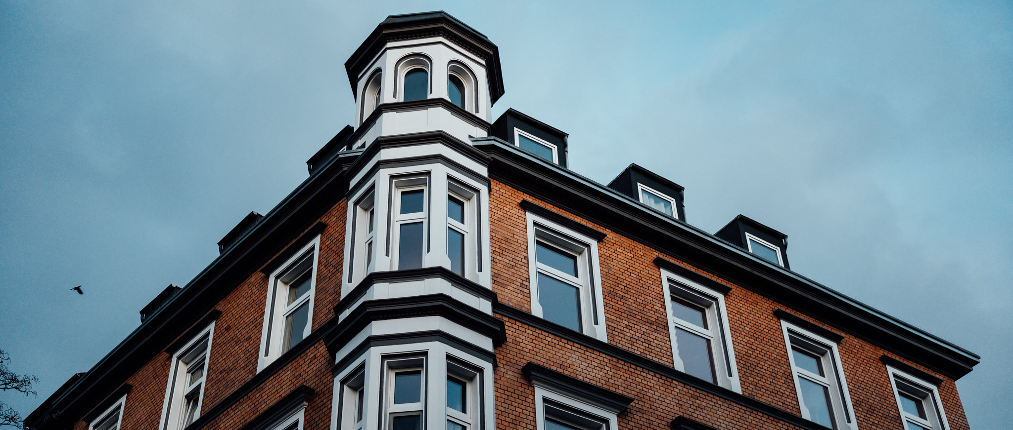 Low-angle shot of a brick building with a bay window and small tower.