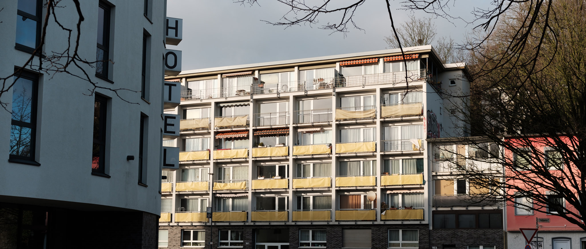 Exterior of a hotel with balconies, adjacent building with 'HOTEL' sign.