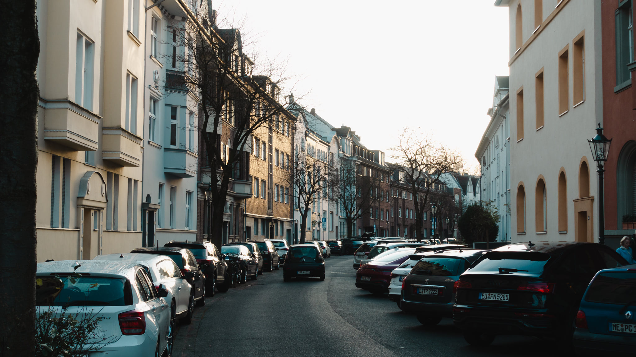 A german street lined with parked cars and old buildings.