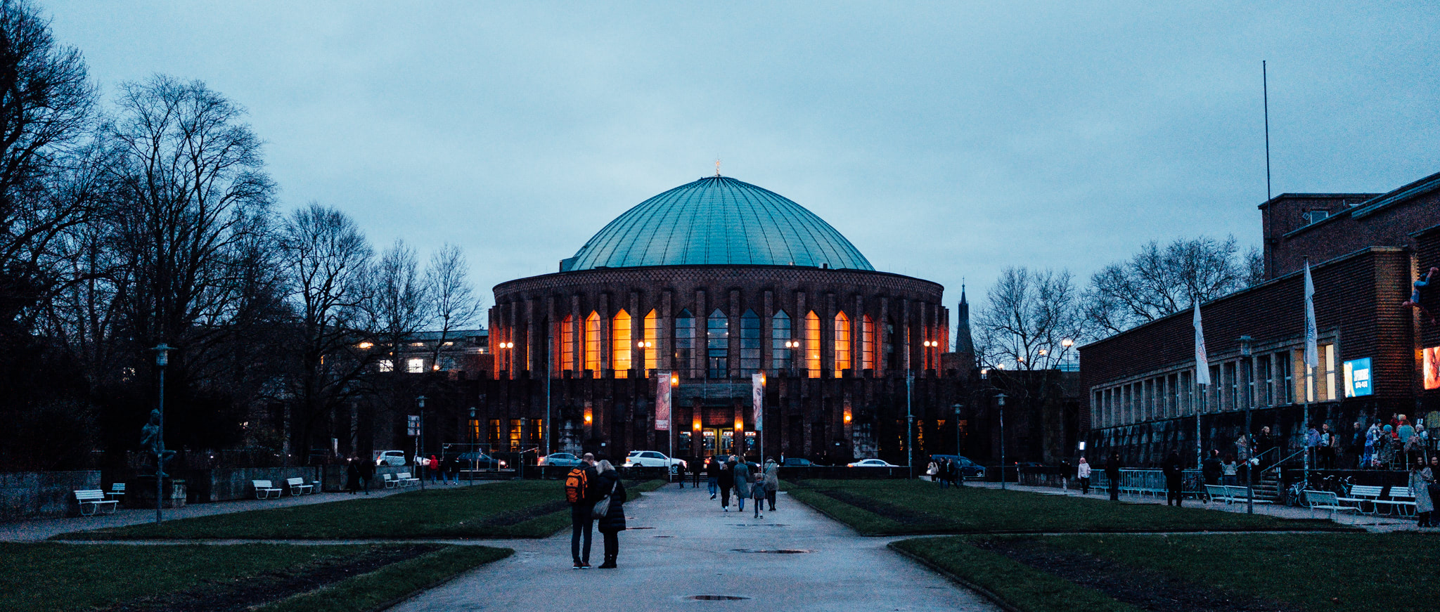 The Tonhalle Düsseldorf concert hall at dusk, featuring a large dome illuminated with orange light.