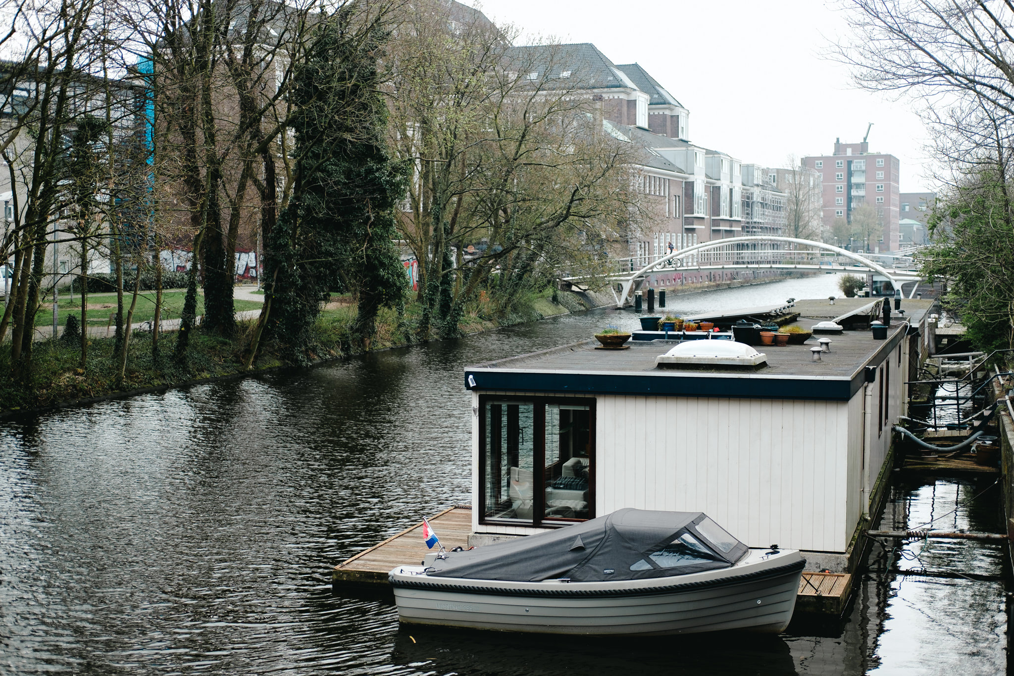 Houseboat on Amsterdam canal with small boat alongside.