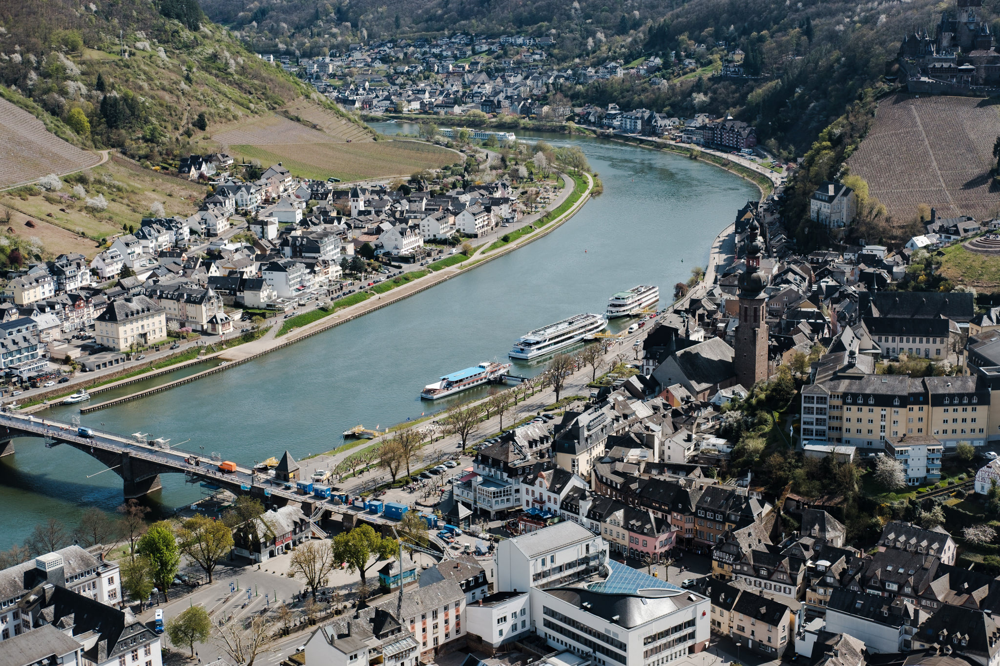 Aerial view of a town bisected by a river, with surrounding hills.