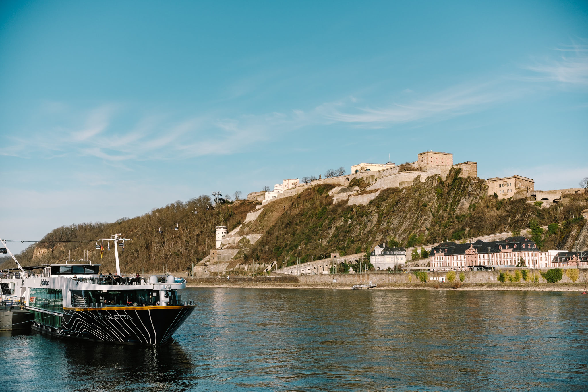 A river cruise boat docked below Ehrenbreitstein Fortress.