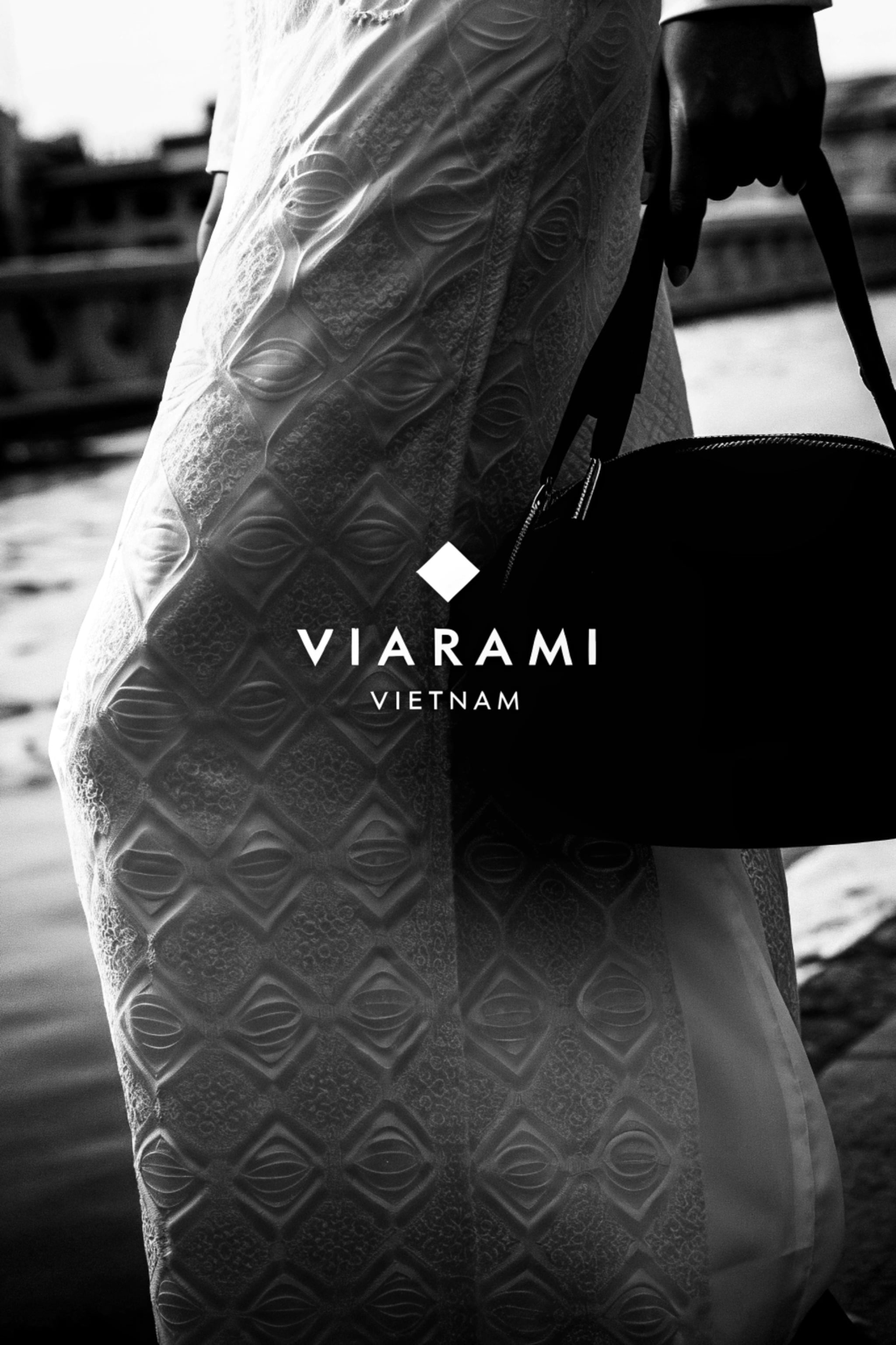 Close-up of a woman in a patterned Ao Dai dress, holding a round bag.