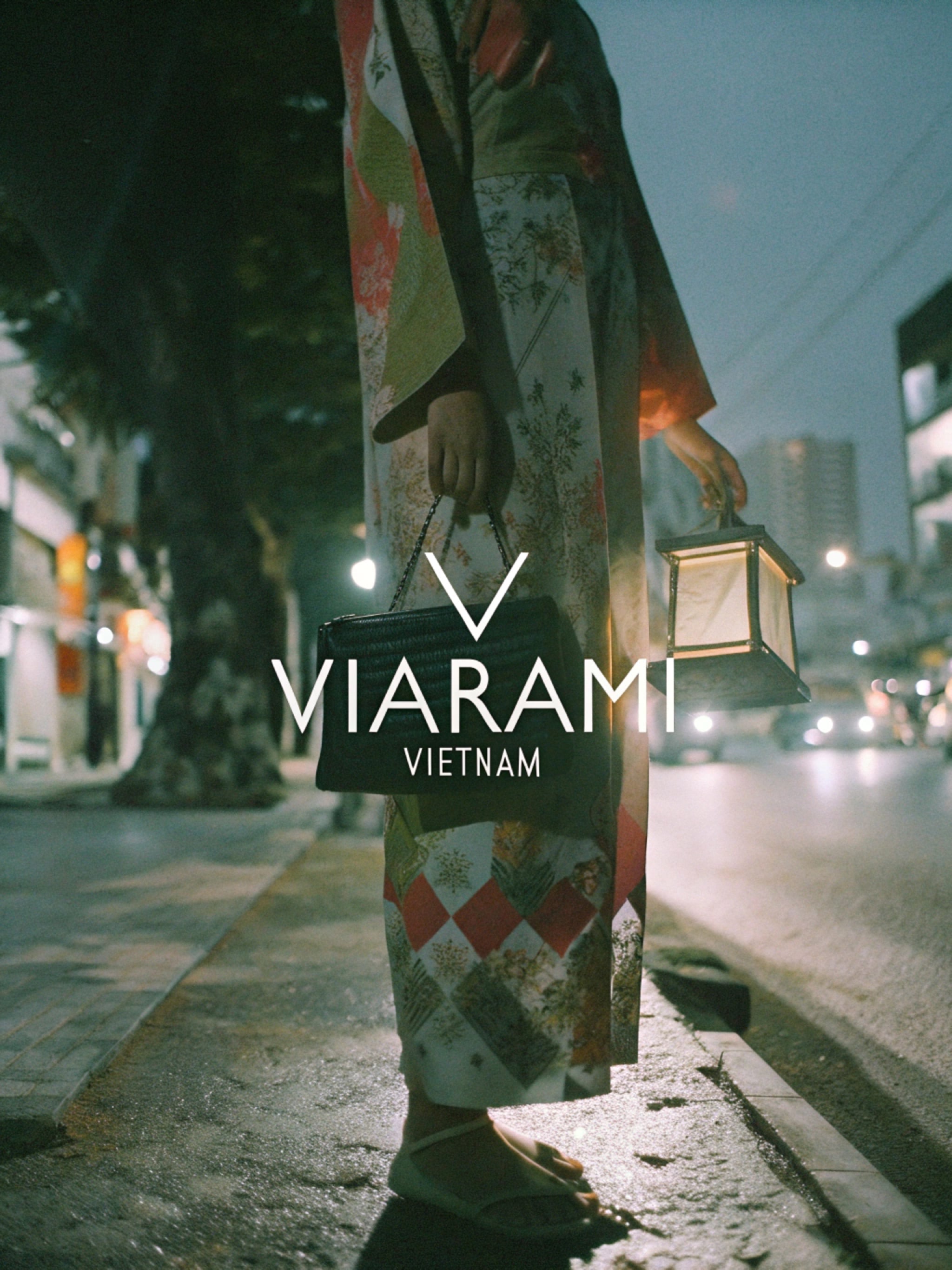 Woman in kimono holding lantern and handbag at night.