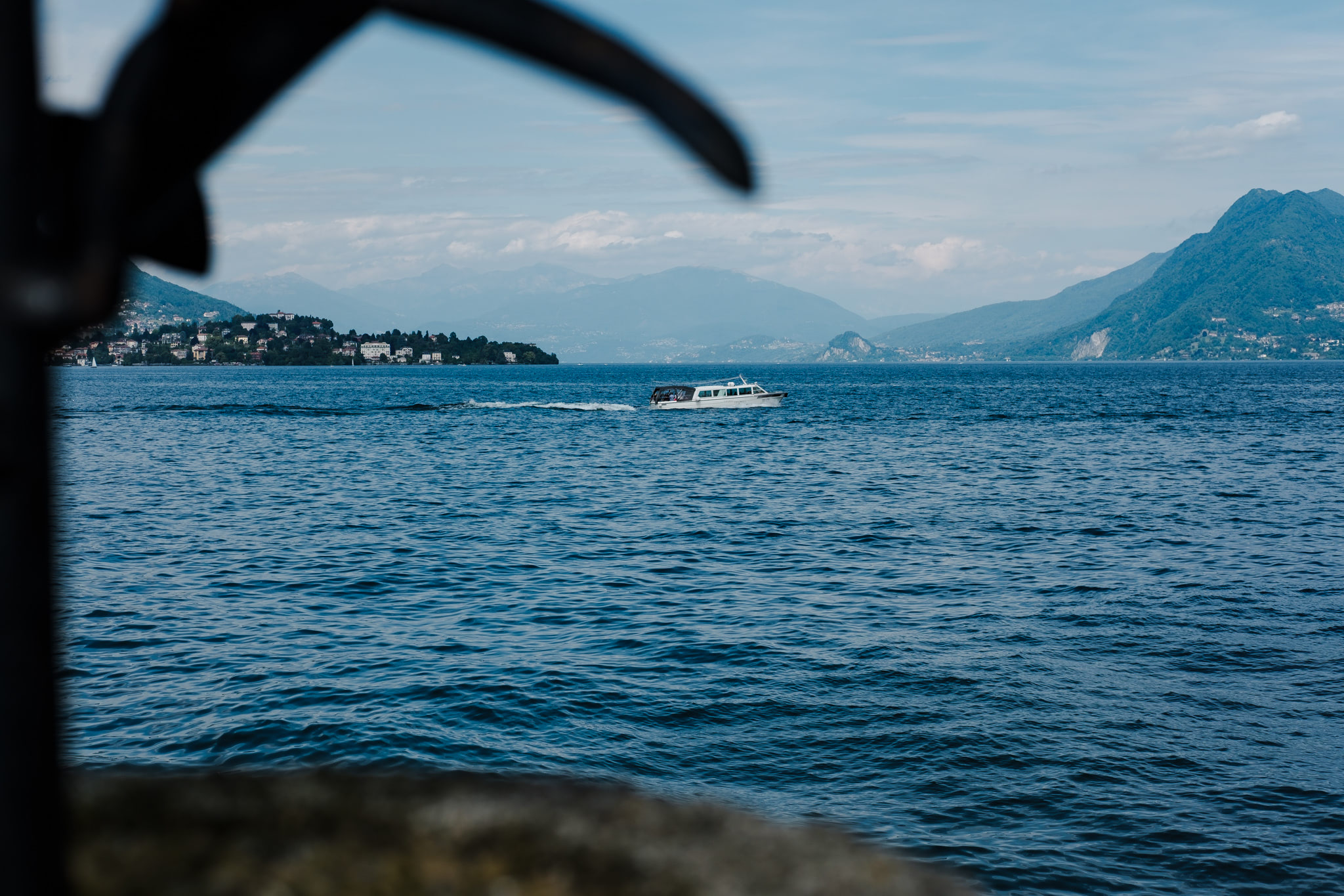 Boat on a lake with mountains in the background, viewed through a dark, abstract shape.