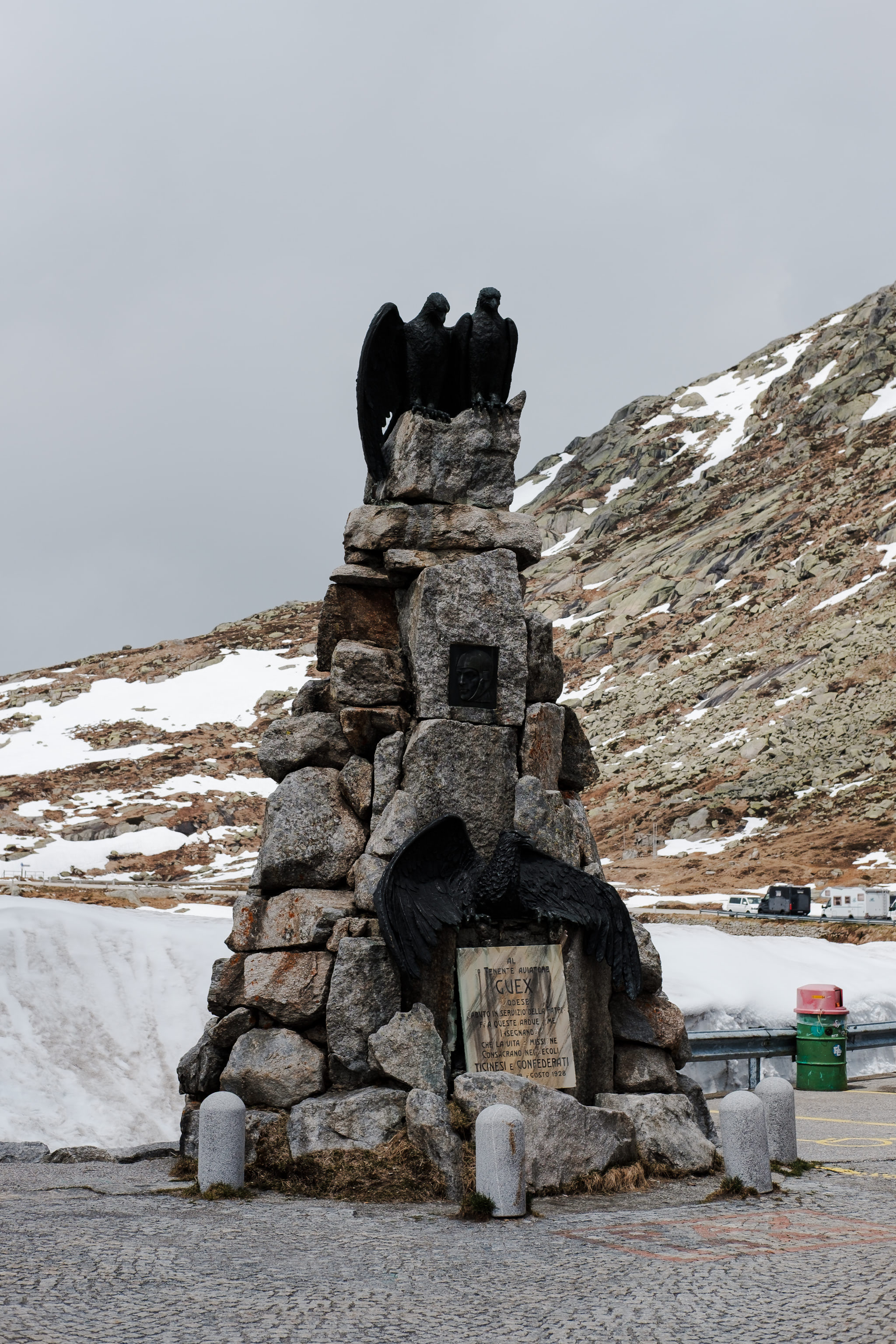 Monument with eagle statues in a mountain landscape. Winter scene with snow and gray sky.