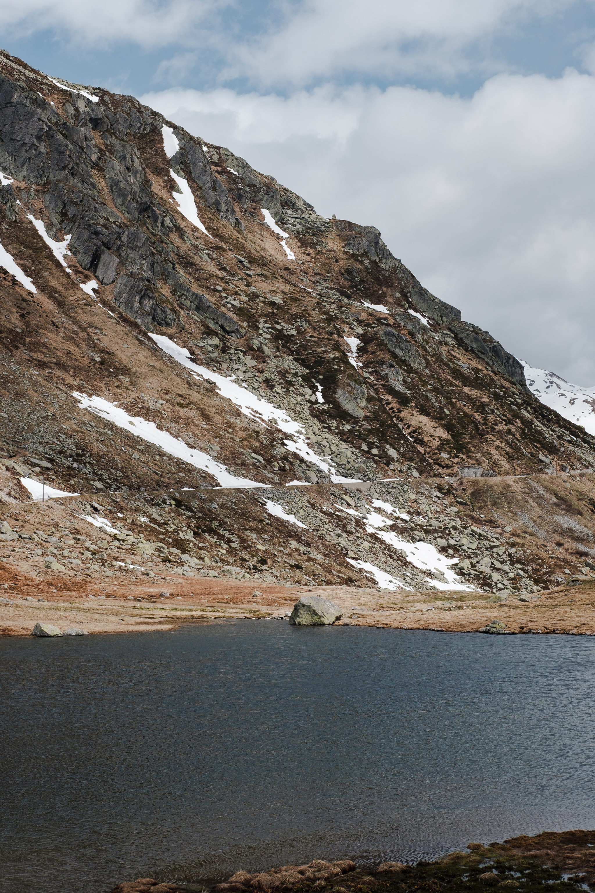 Mountain scene with lake, mountain, snow, and clouds.