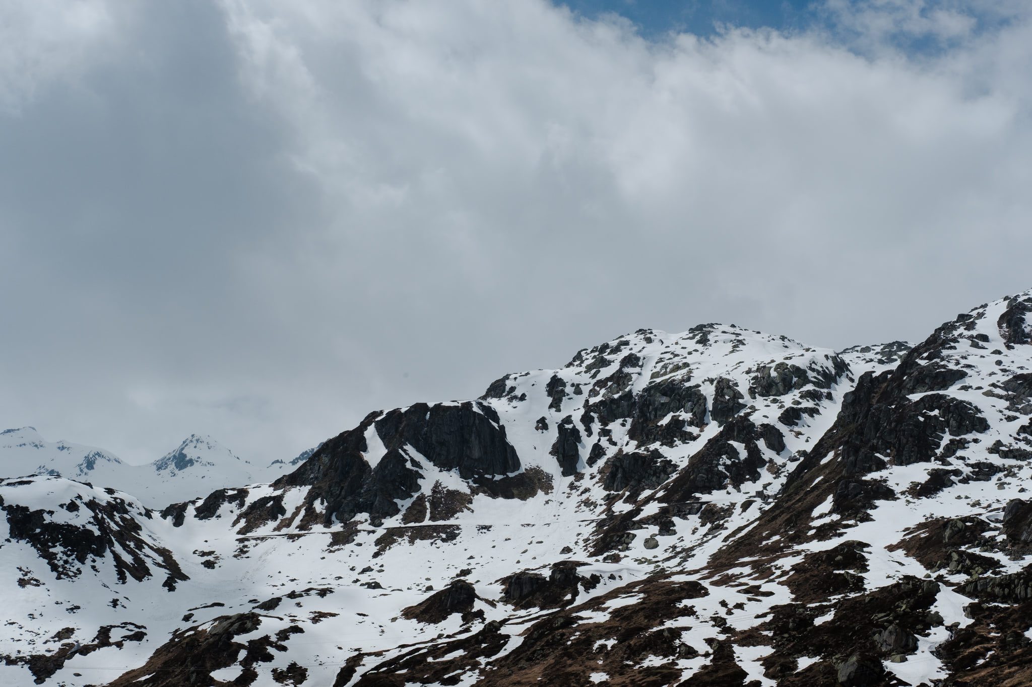 Snow-covered mountain range under a cloudy sky.
