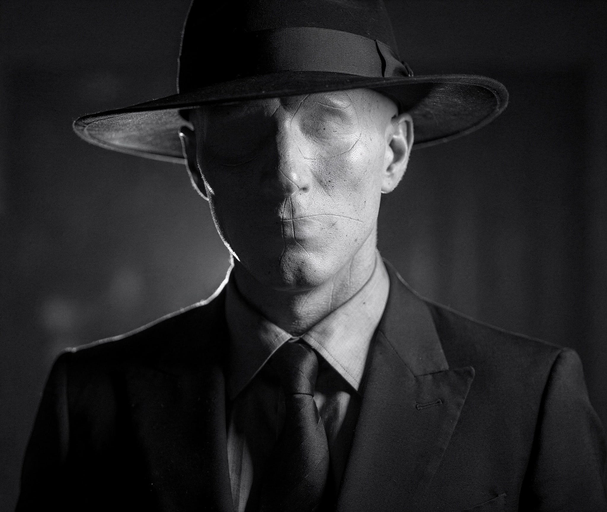 Black and white photo-realistic portrait of a faceless man in a suit and black hat