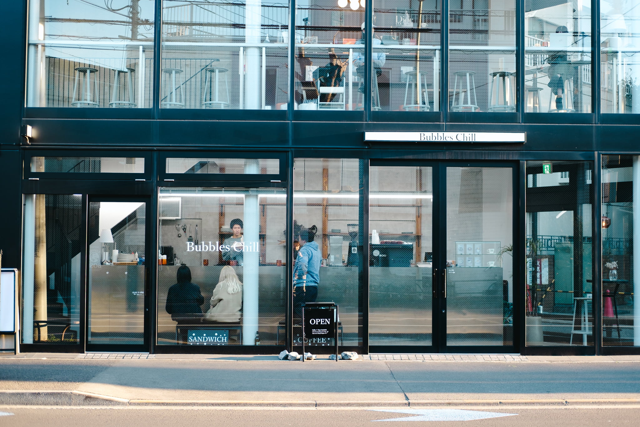 Modern exterior view of Bubbles Chill cafe with large glass windows and patrons inside.