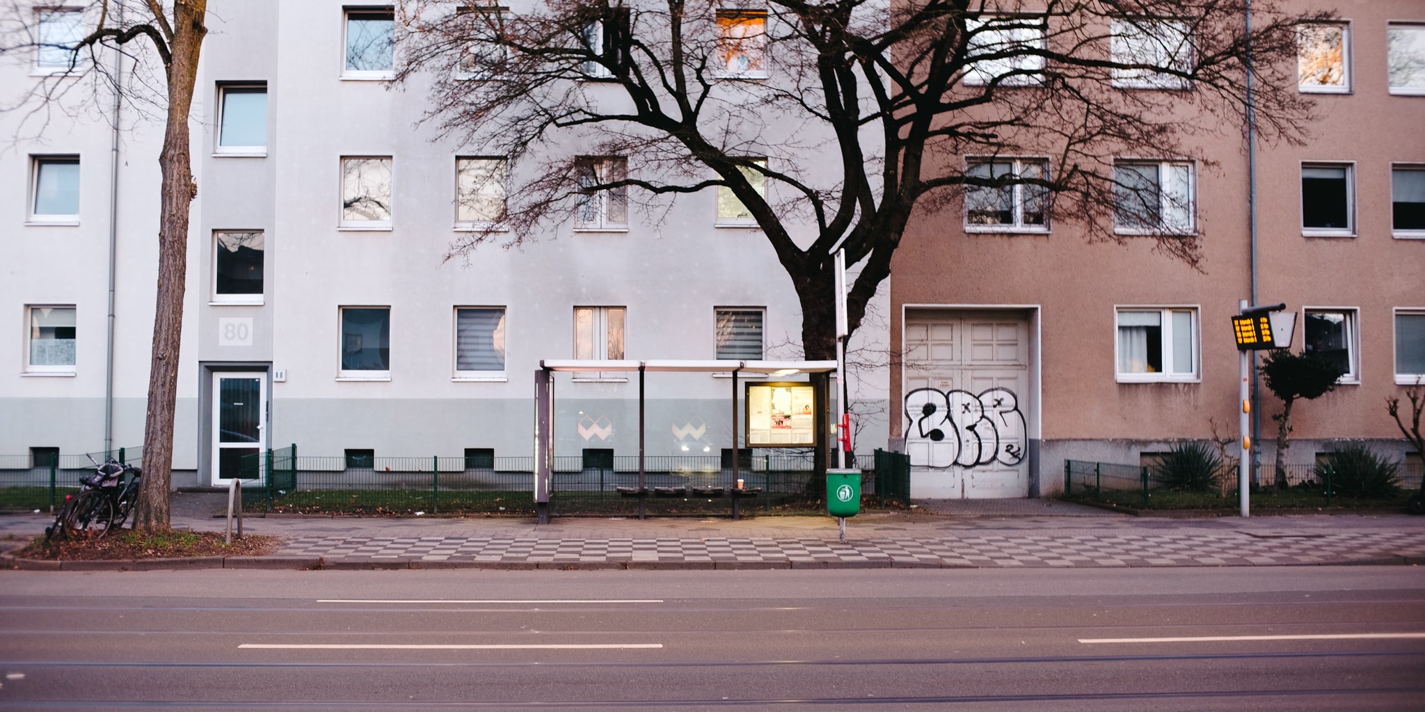 Bus stop shelter on a city sidewalk in front of an apartment building.