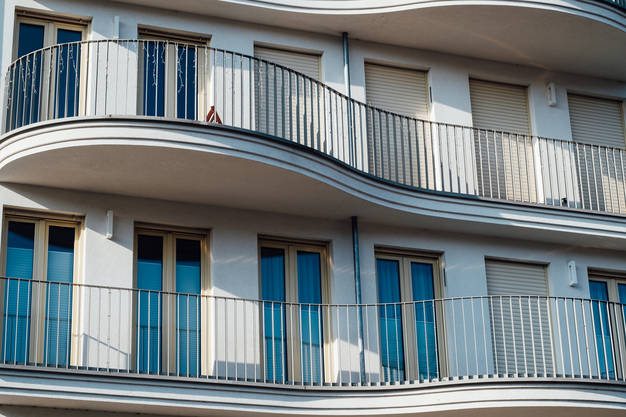 Exterior view of modern apartment building with curved balconies and closed window shutters.