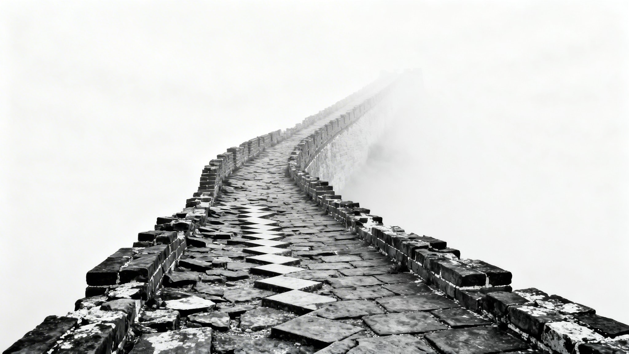 Black and white photo of a crumbling Great Wall path disappearing into dense fog