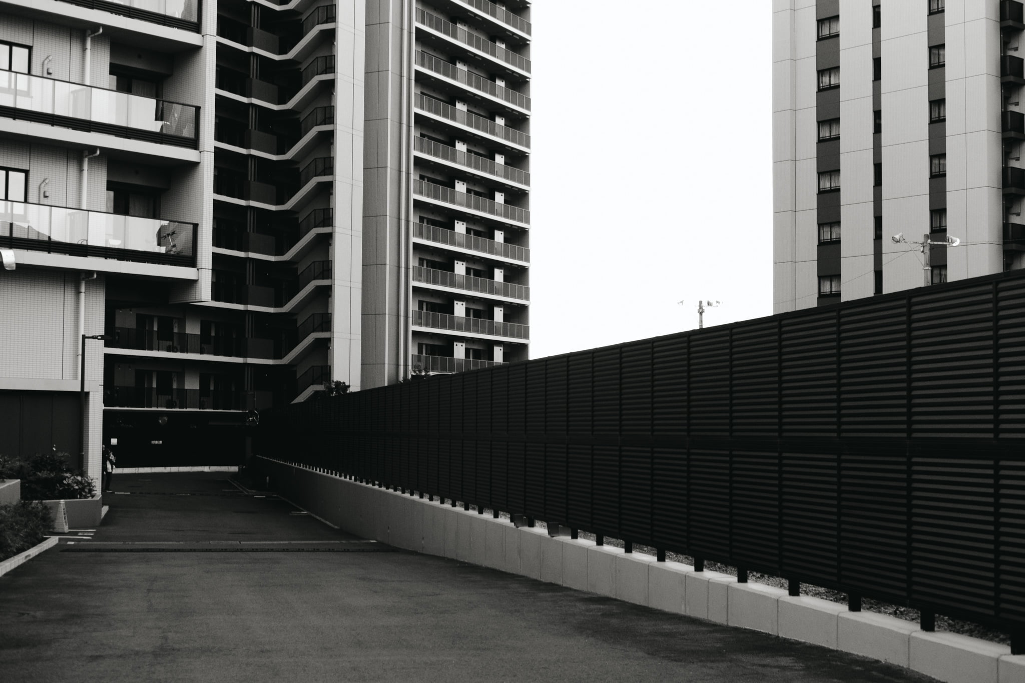 Modern apartment complex with balconies and a tall black privacy fence.