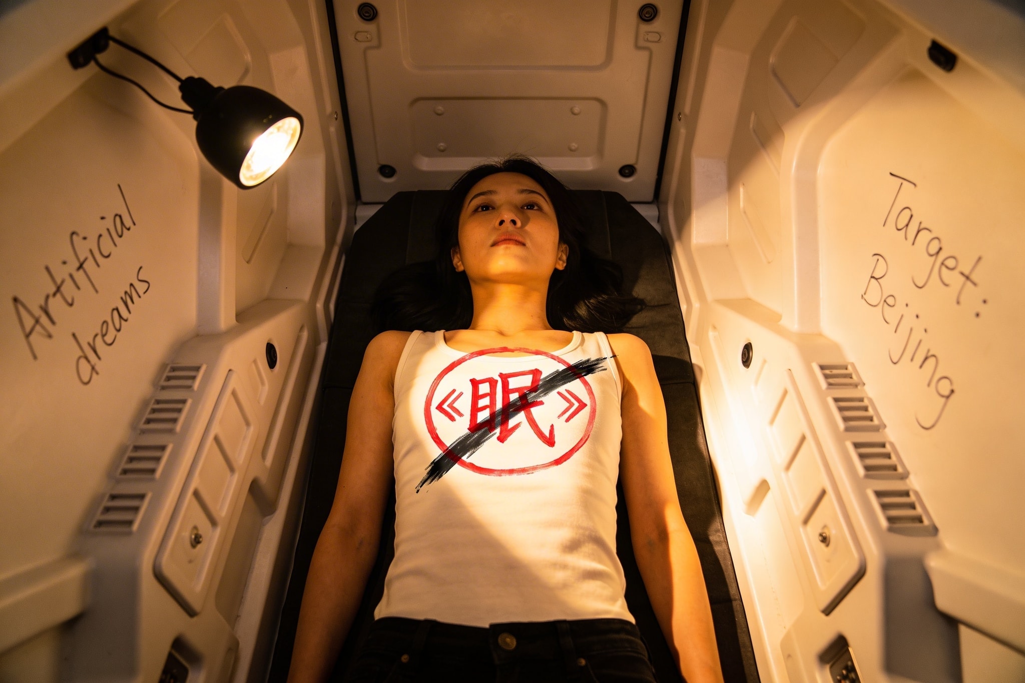 A woman in a white minimalist sleeper pod with a crossed-out red 'Sleep' symbol on her chest and etched notes