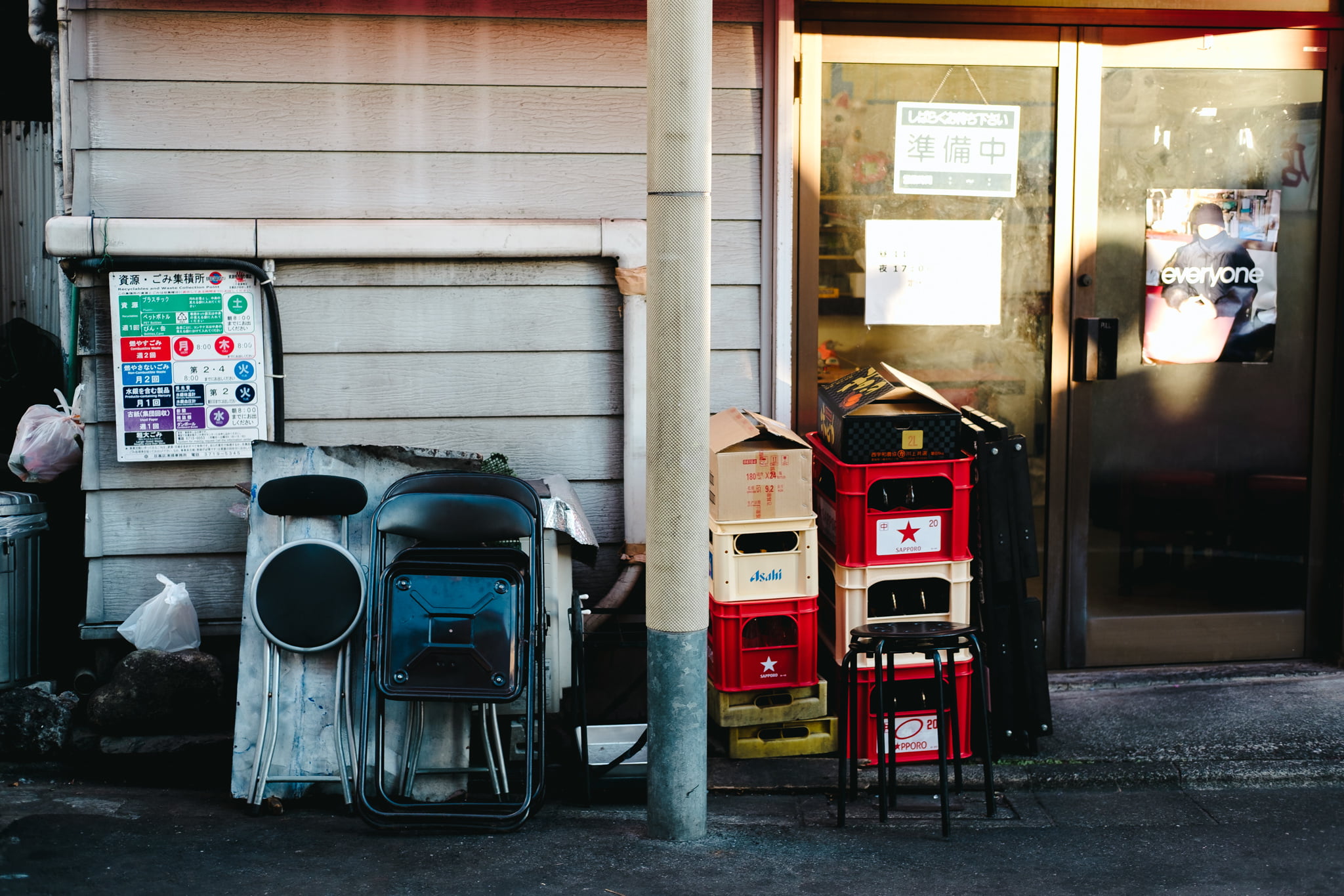 A stack of folding chairs and plastic beer crates outside a small shop in Japan.