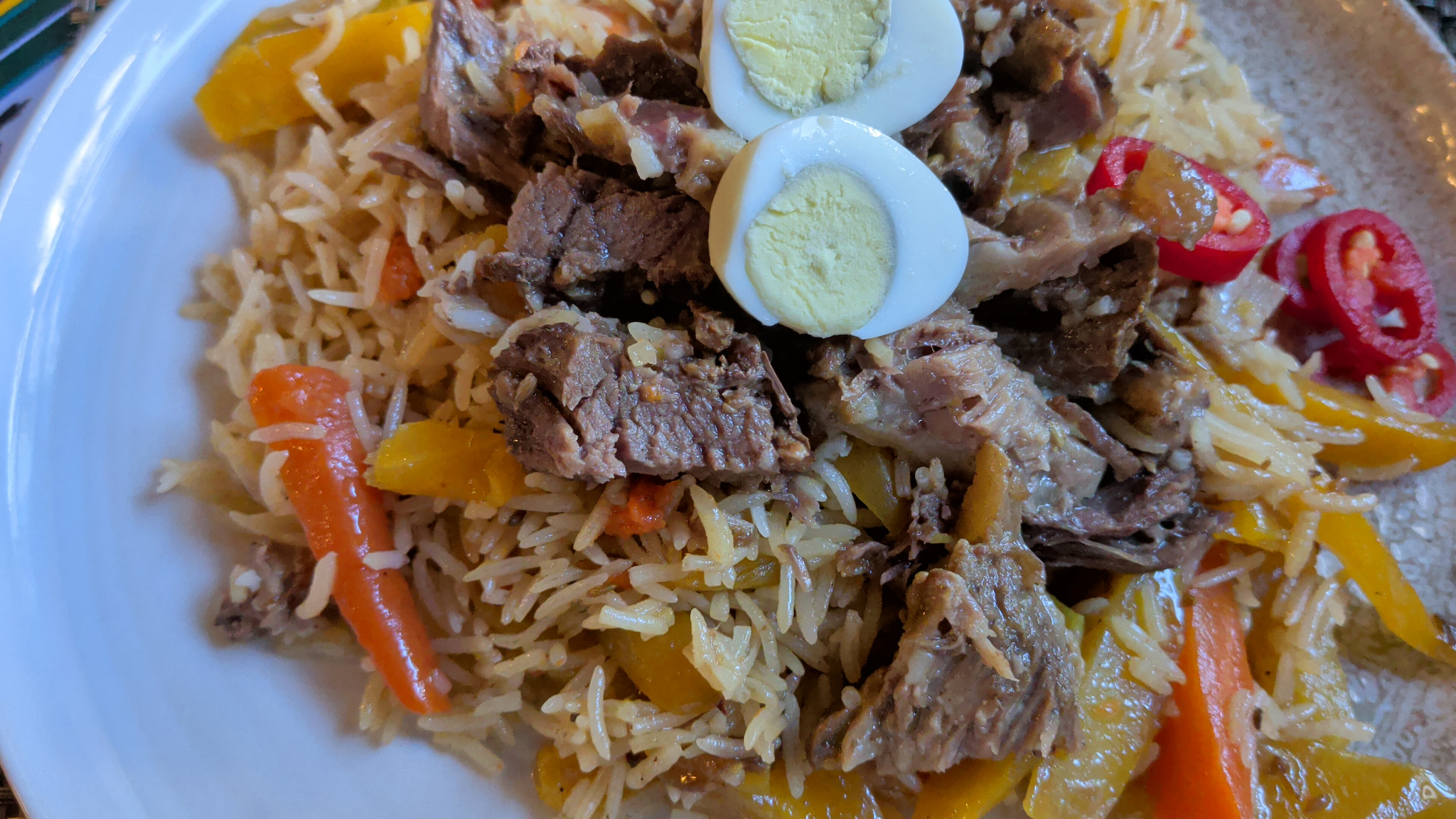 Rice pilaf topped with slow-cooked meat and boiled egg.