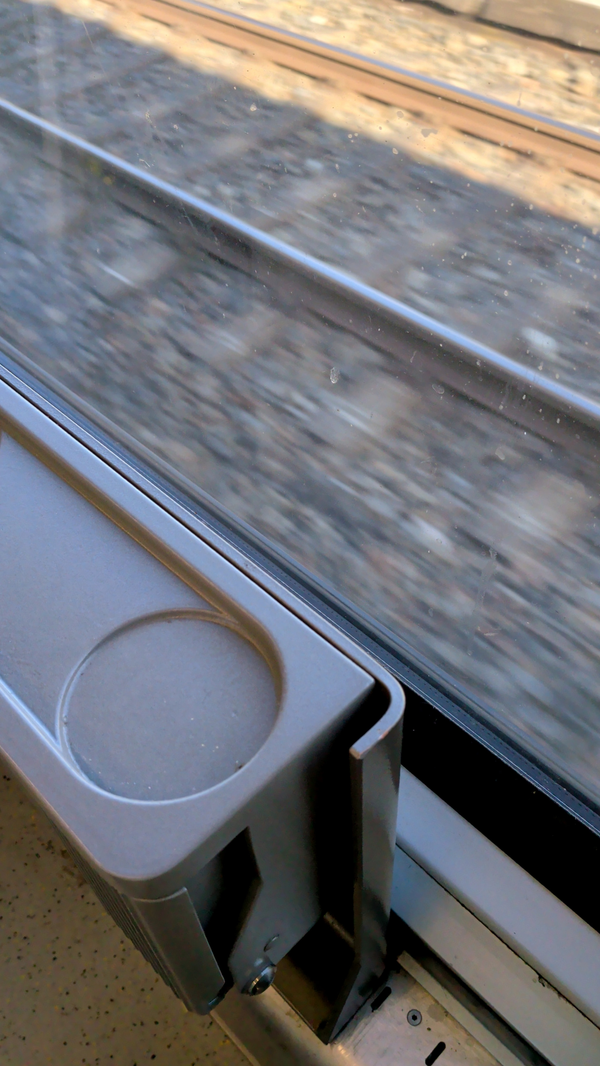 View from a train window showing a folding tray table and motion-blurred tracks.