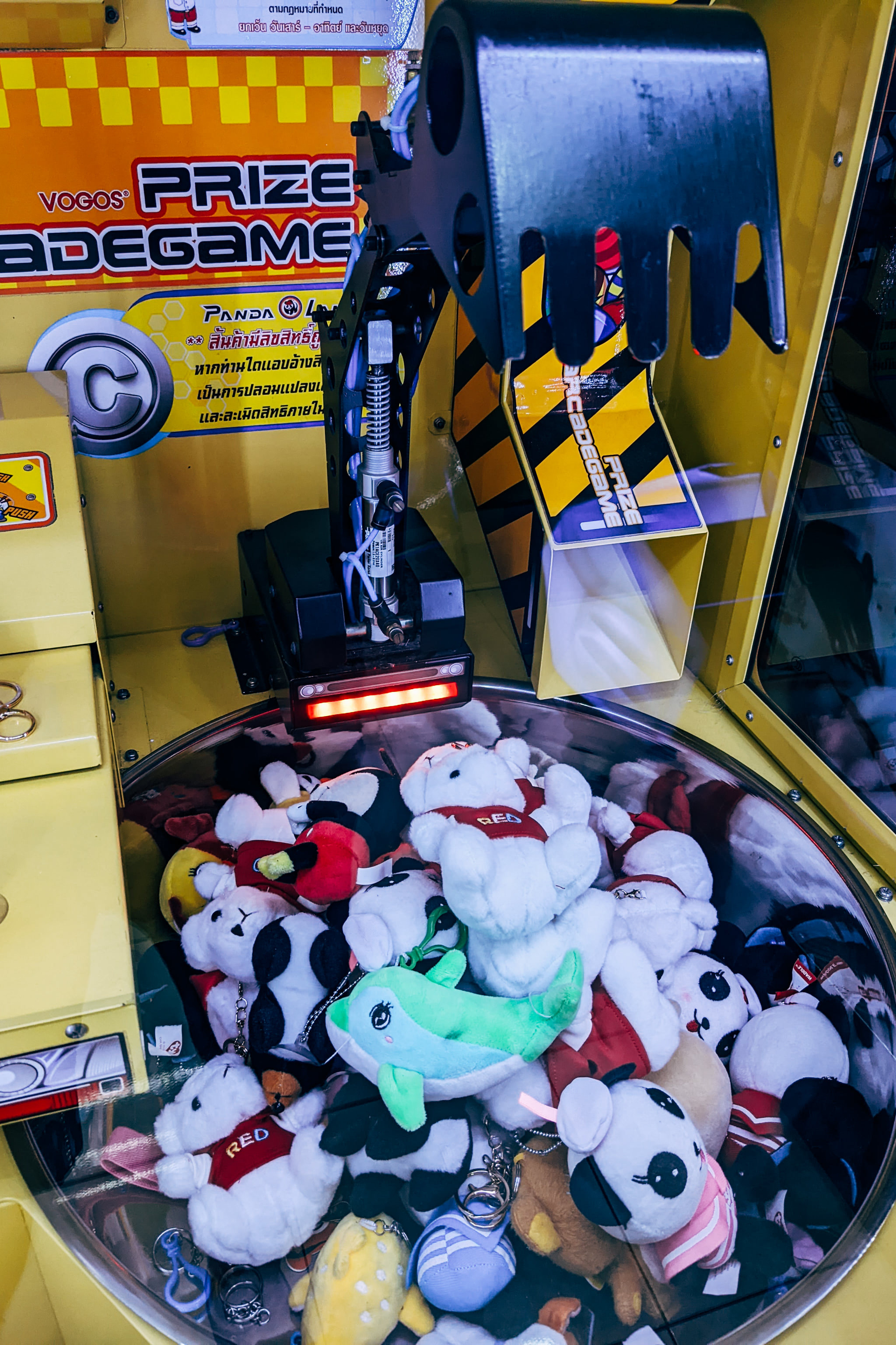 A close-up view of an arcade claw machine filled with various small plush toys.