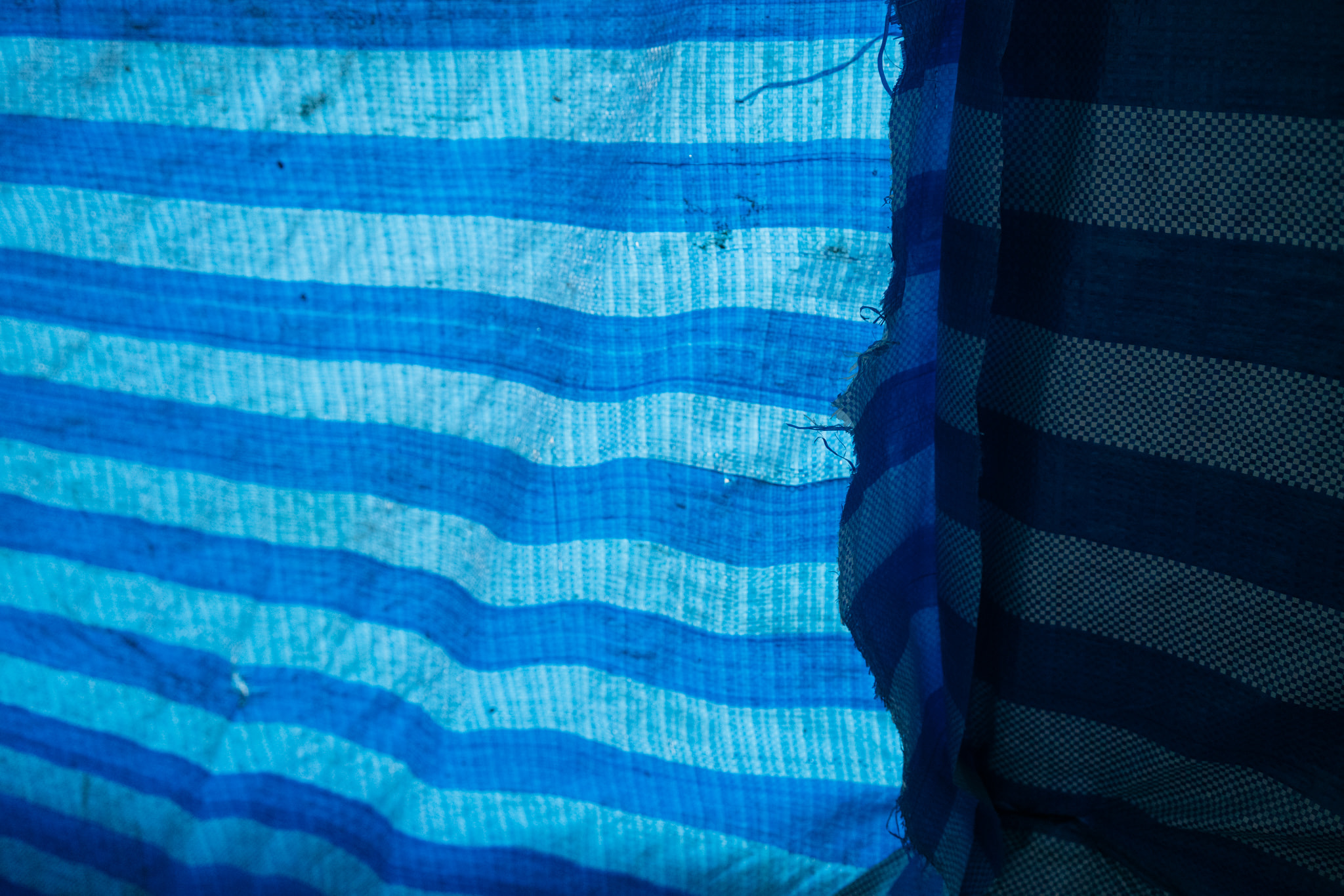 Blue striped woven tarp fabric with frayed edge