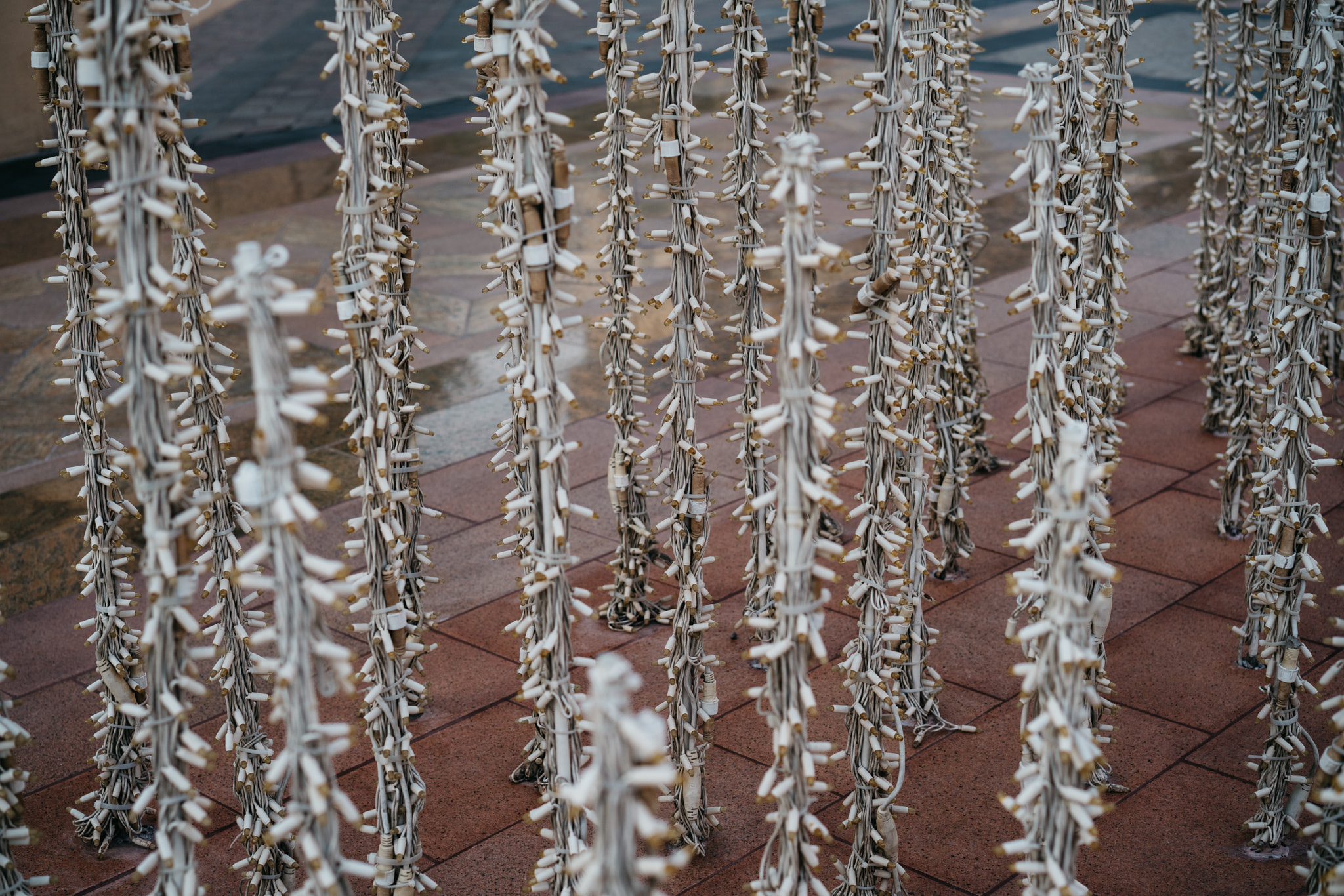 Art installation of bundled cigarette butts on red brick pavement