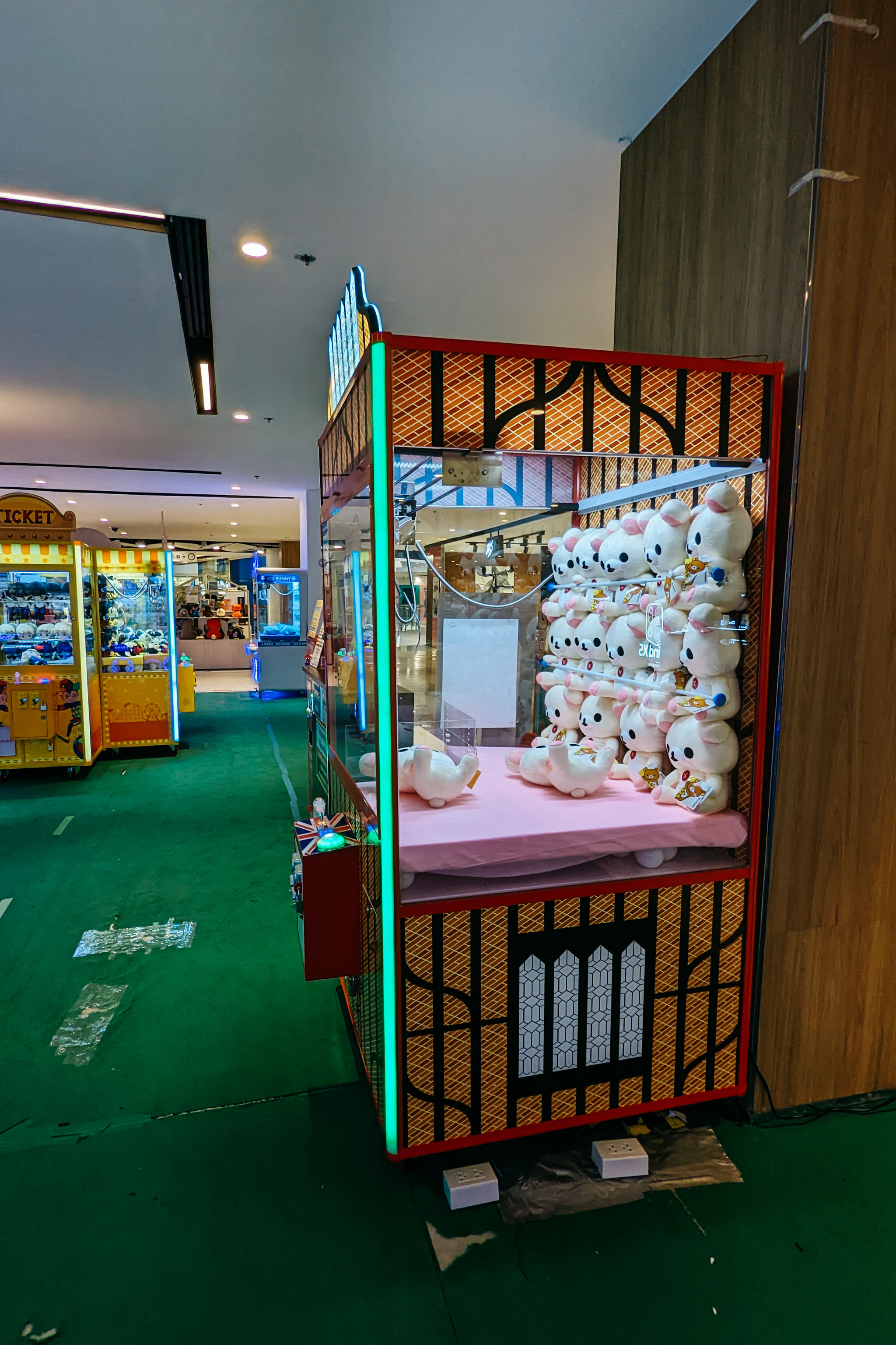 Claw machine with white cat plush toys in arcade