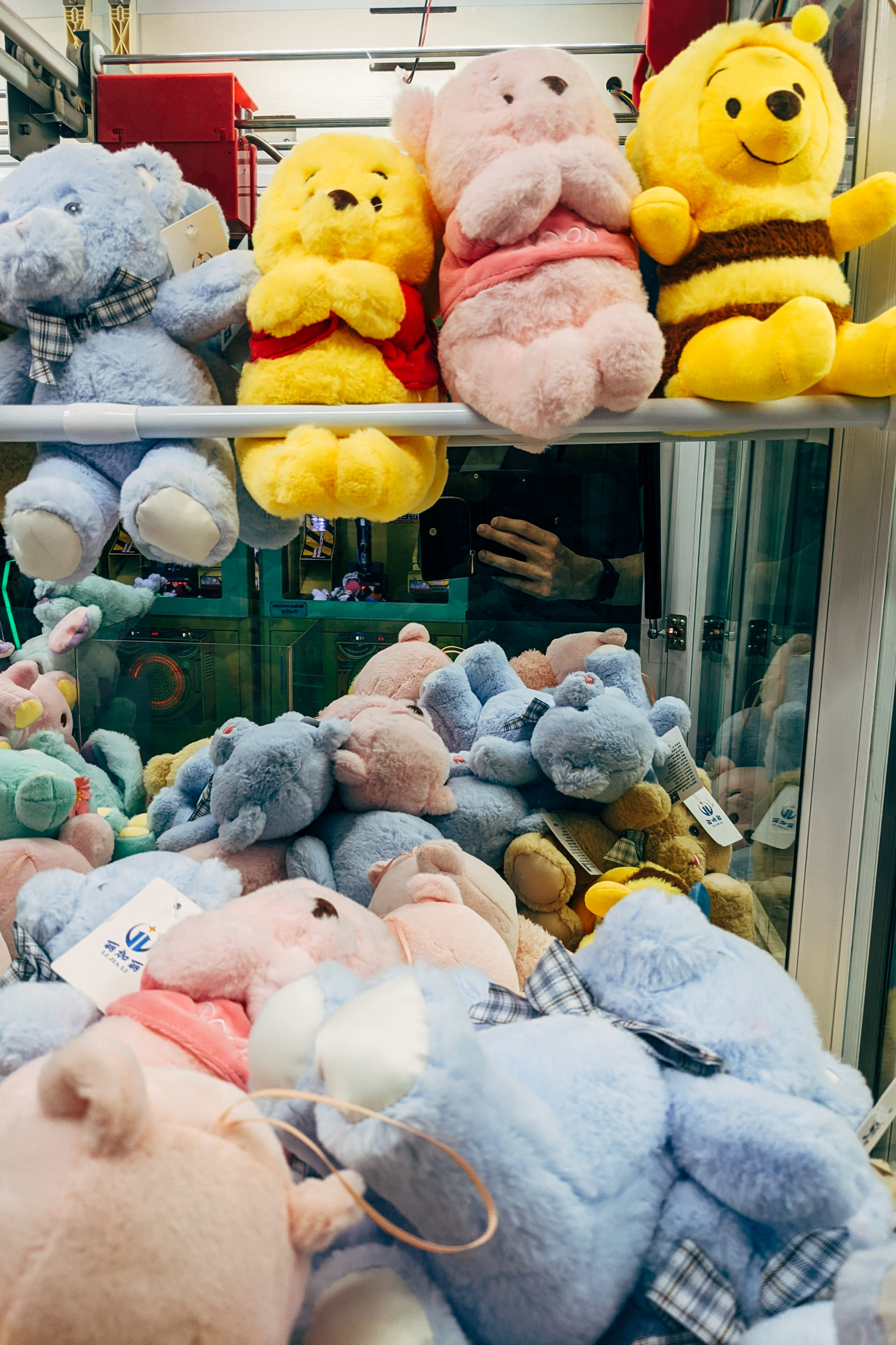 Assortment of colorful plush toys including Winnie the Pooh characters in claw machine