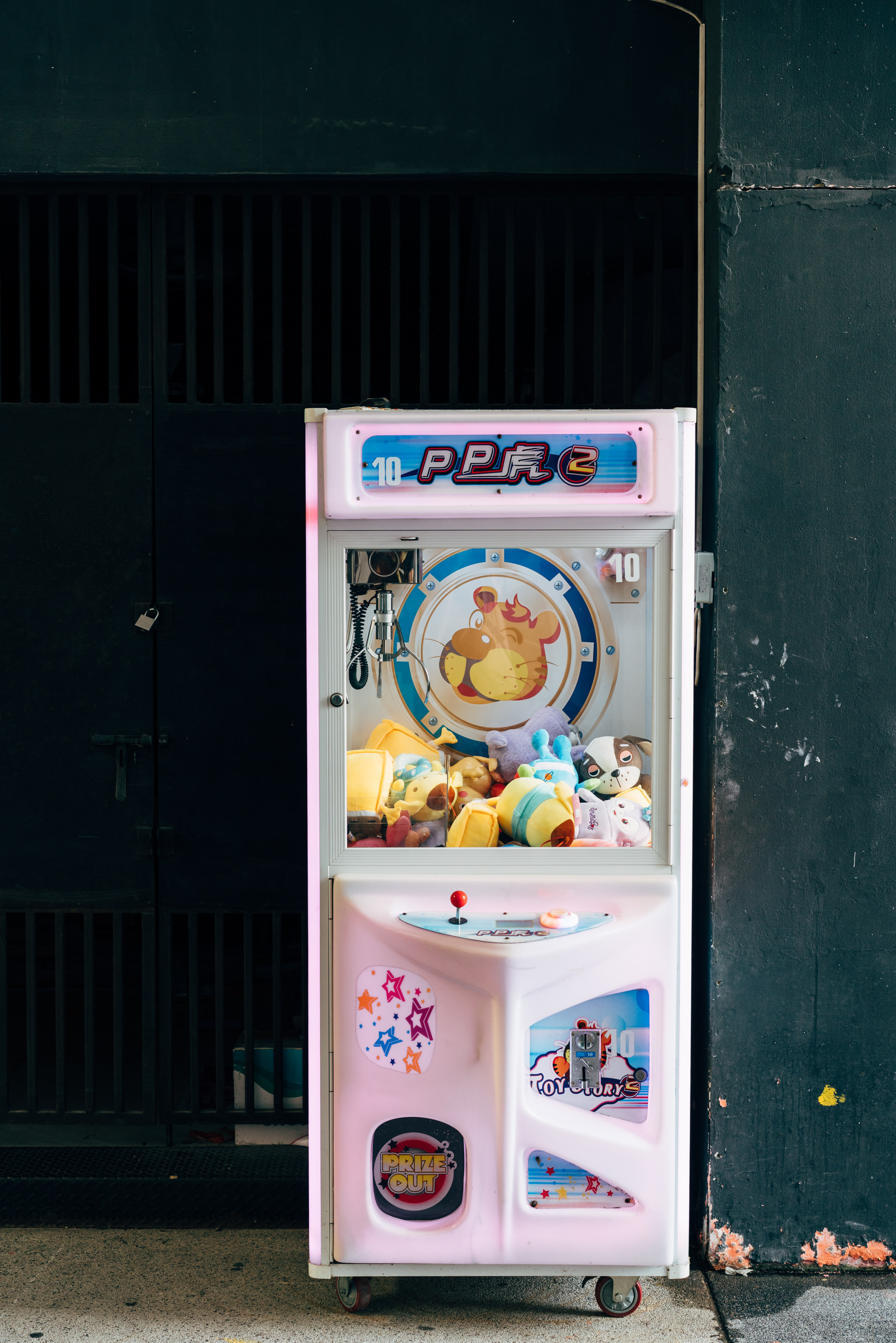 Claw machine filled with colorful stuffed animals on city sidewalk