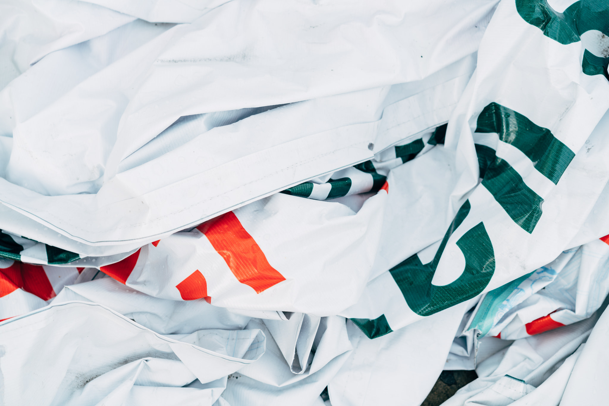 Crumpled white plastic tarps with green and red markings