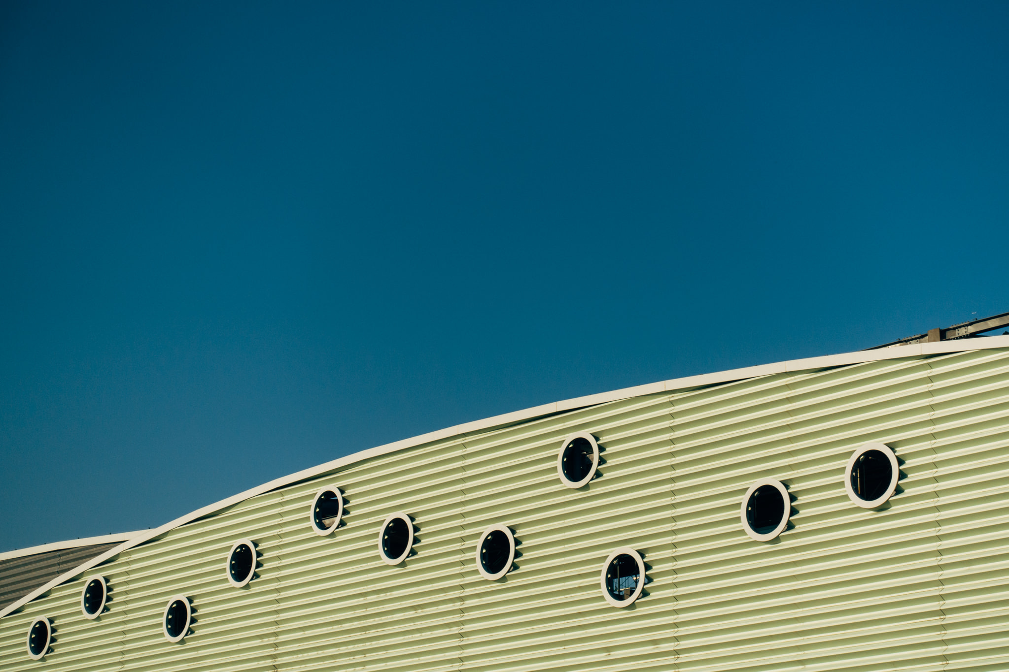 Curved building facade with circular windows against blue sky