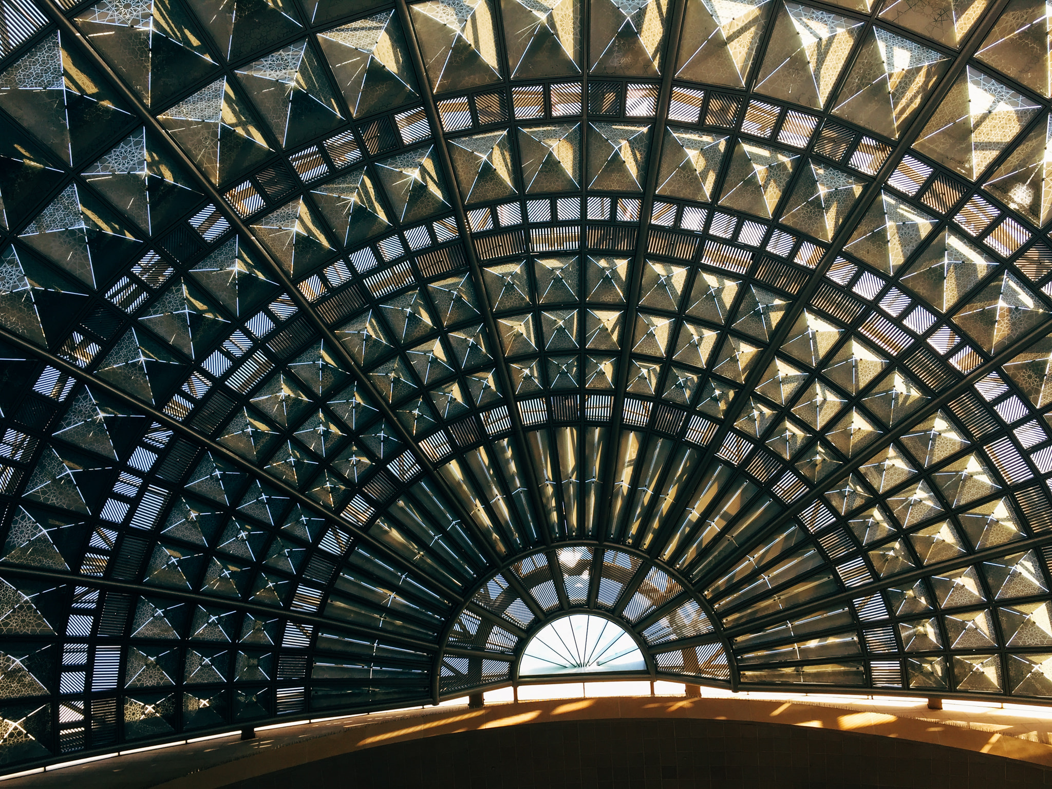 Intricate geometric glass and metal dome ceiling with sunlight filtering through
