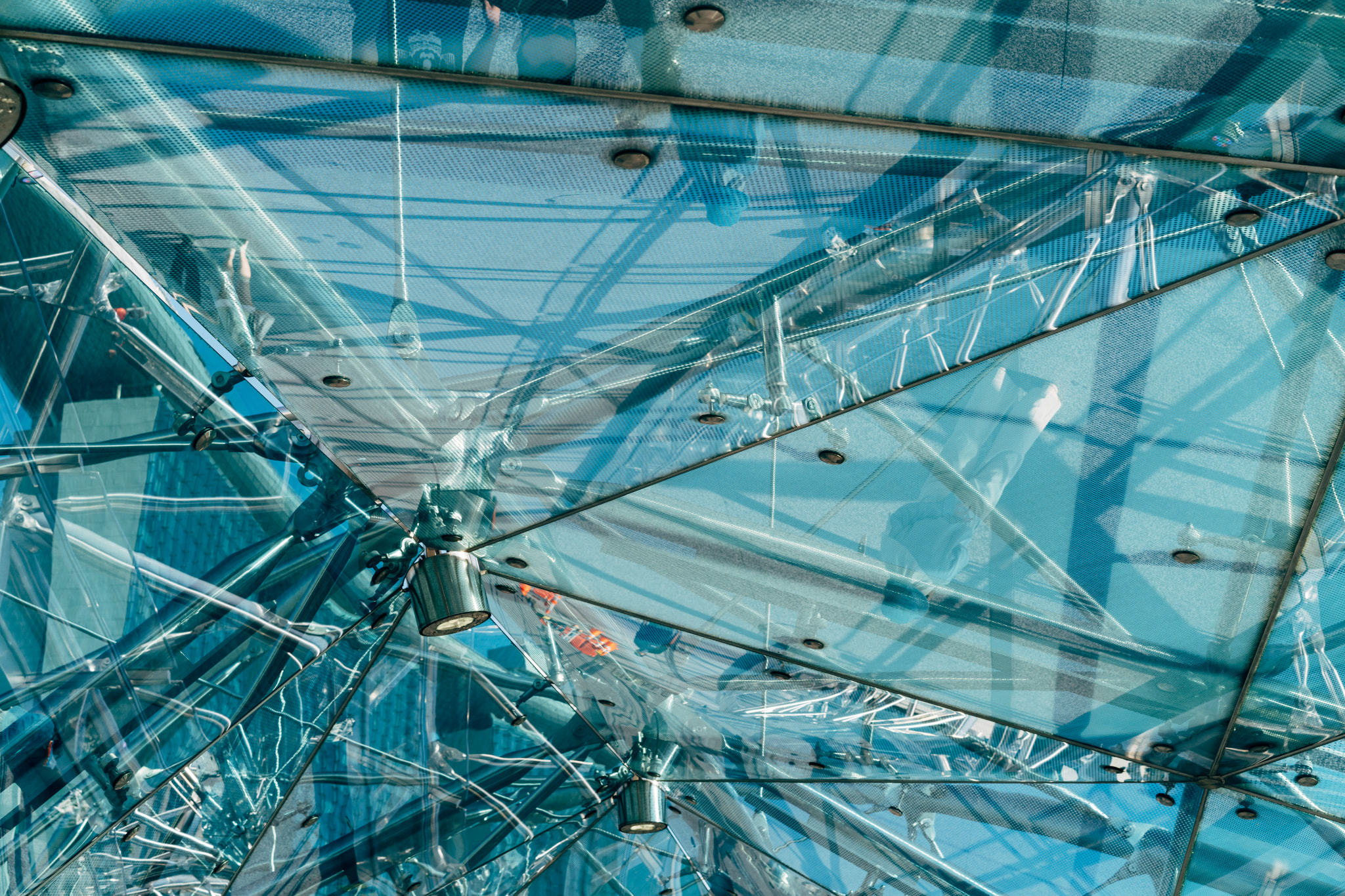 Looking up at modern glass ceiling structure with reflections