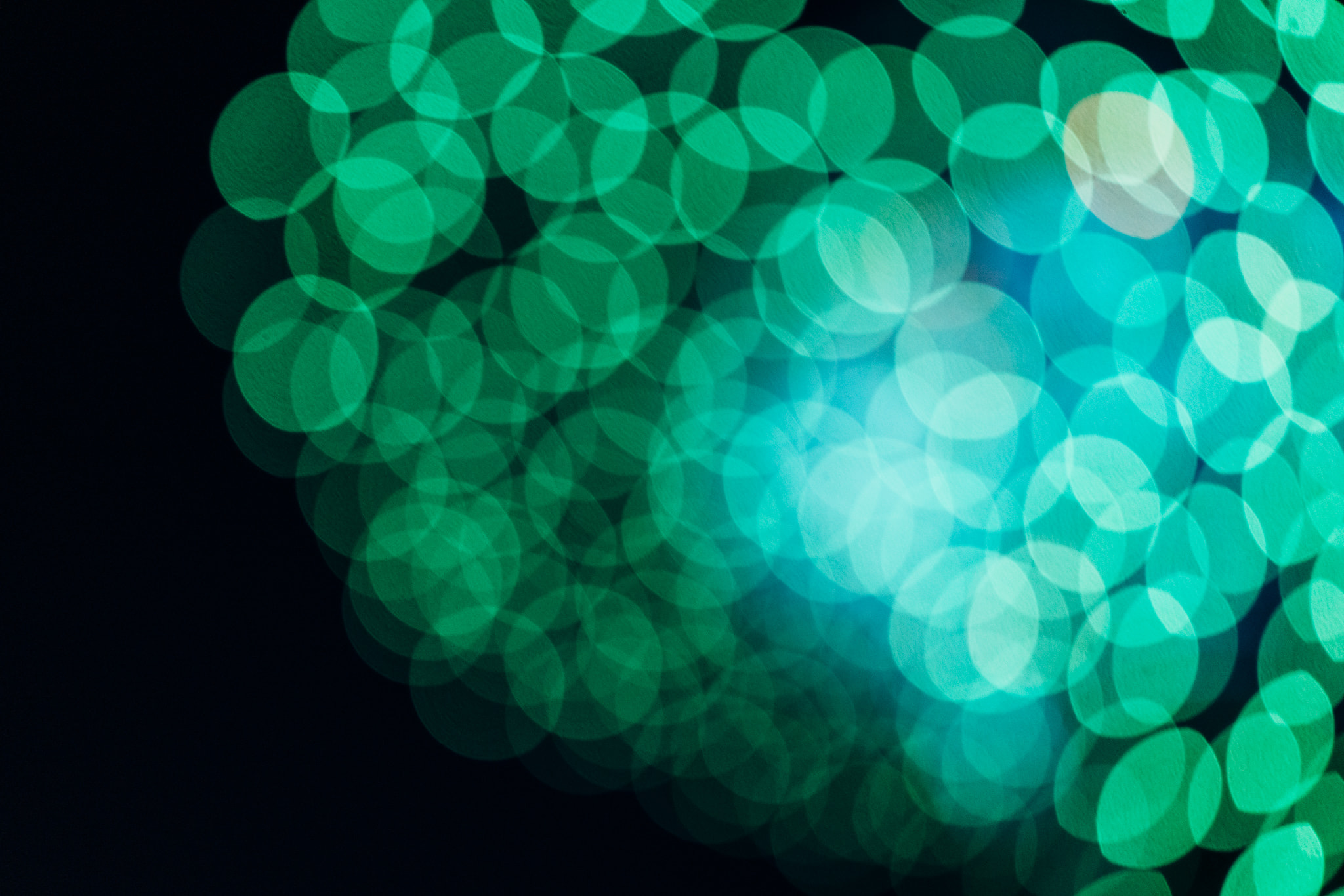 Green and cyan bokeh light circles on black background