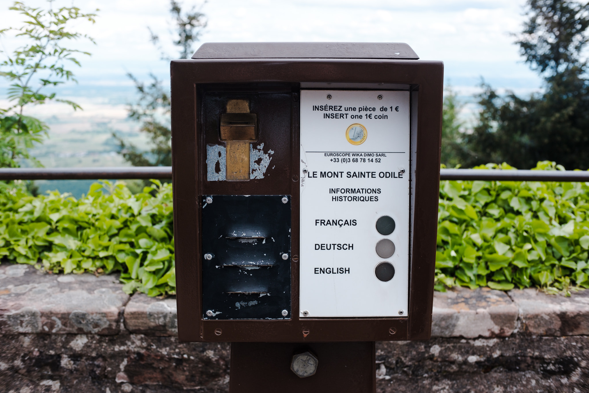 A coin-operated historical information terminal at Le Mont Sainte-Odile outdoors.