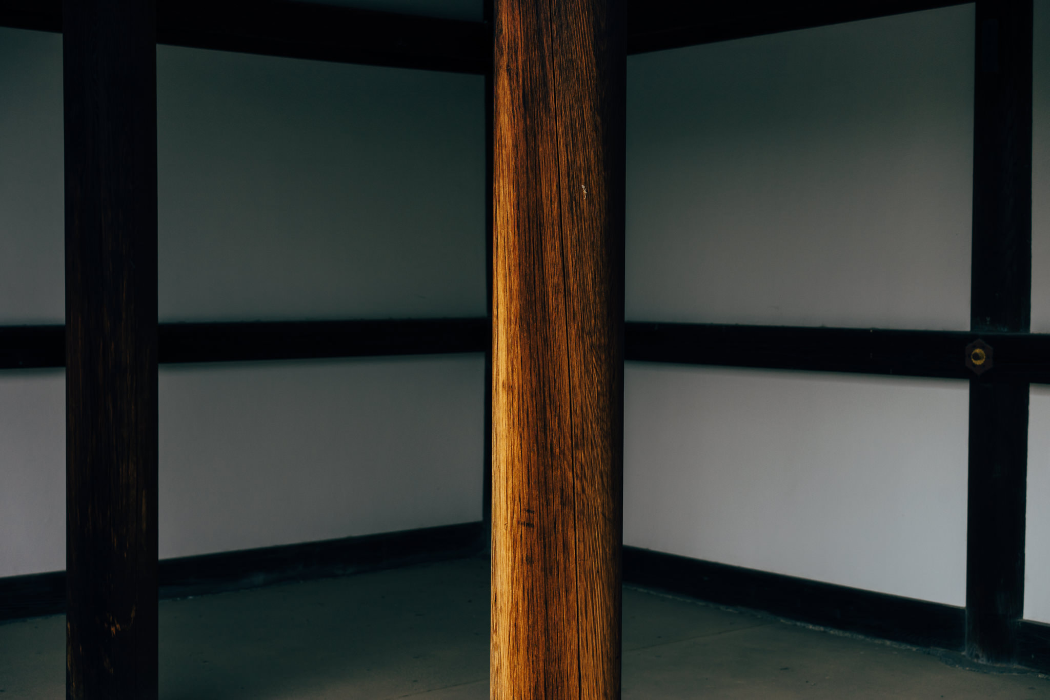 Interior corner of traditional Japanese room with wooden beams and white walls