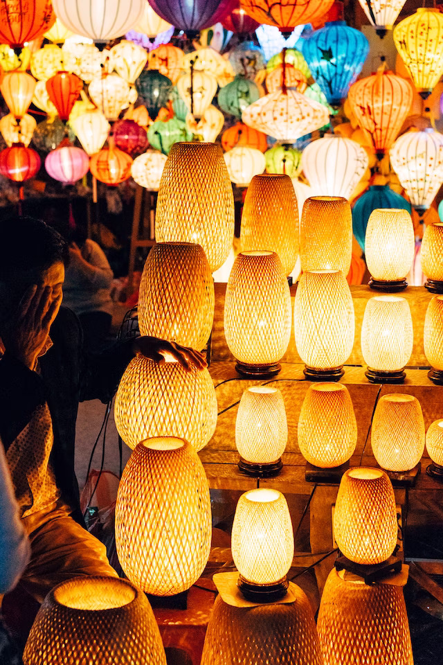 Vendor arranging glowing woven lanterns at a bustling night market
