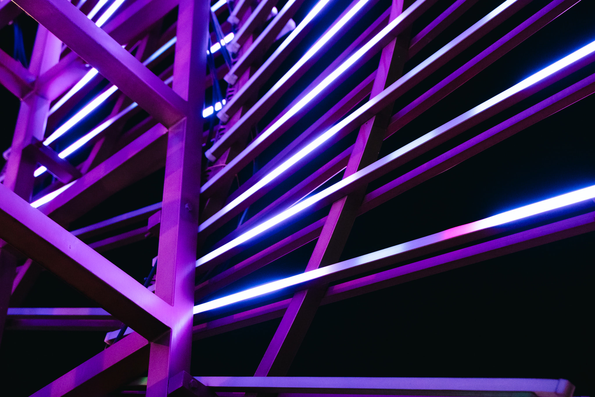 Abstract geometric structure with purple neon light tubes against black background