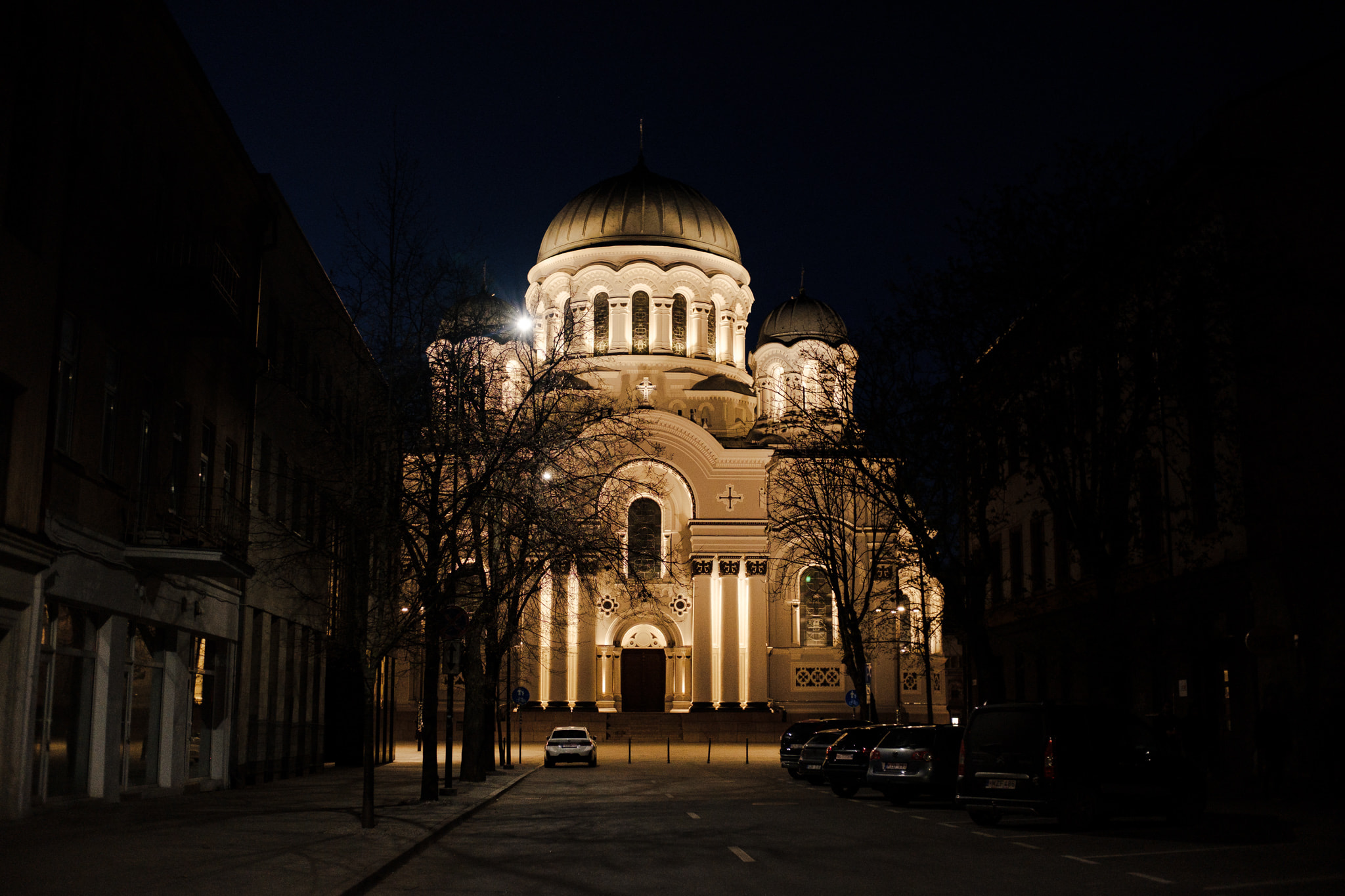 Night view of illuminated orthodox cathedral with domes on city street
