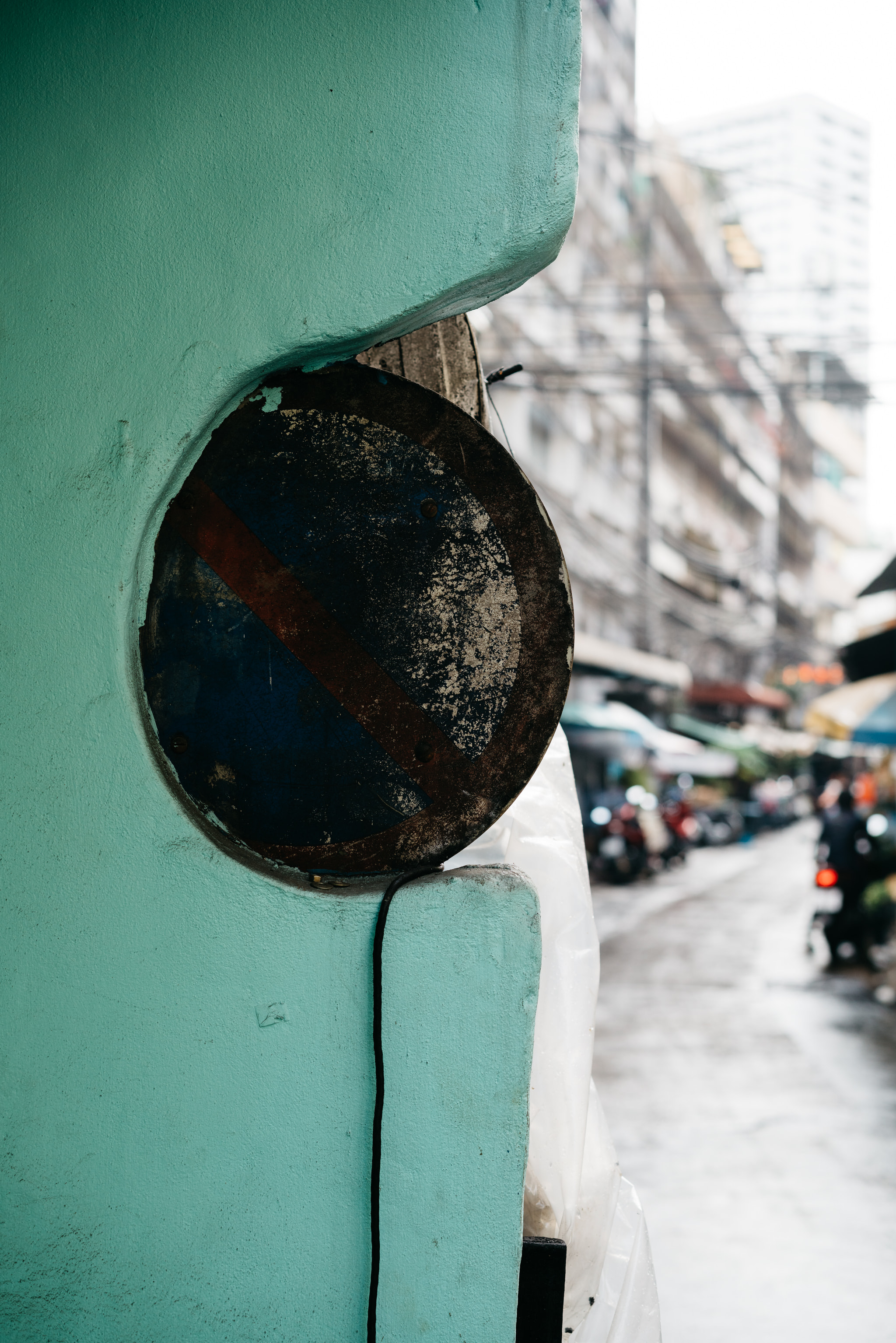 Circular no parking sign embedded in turquoise wall on urban street