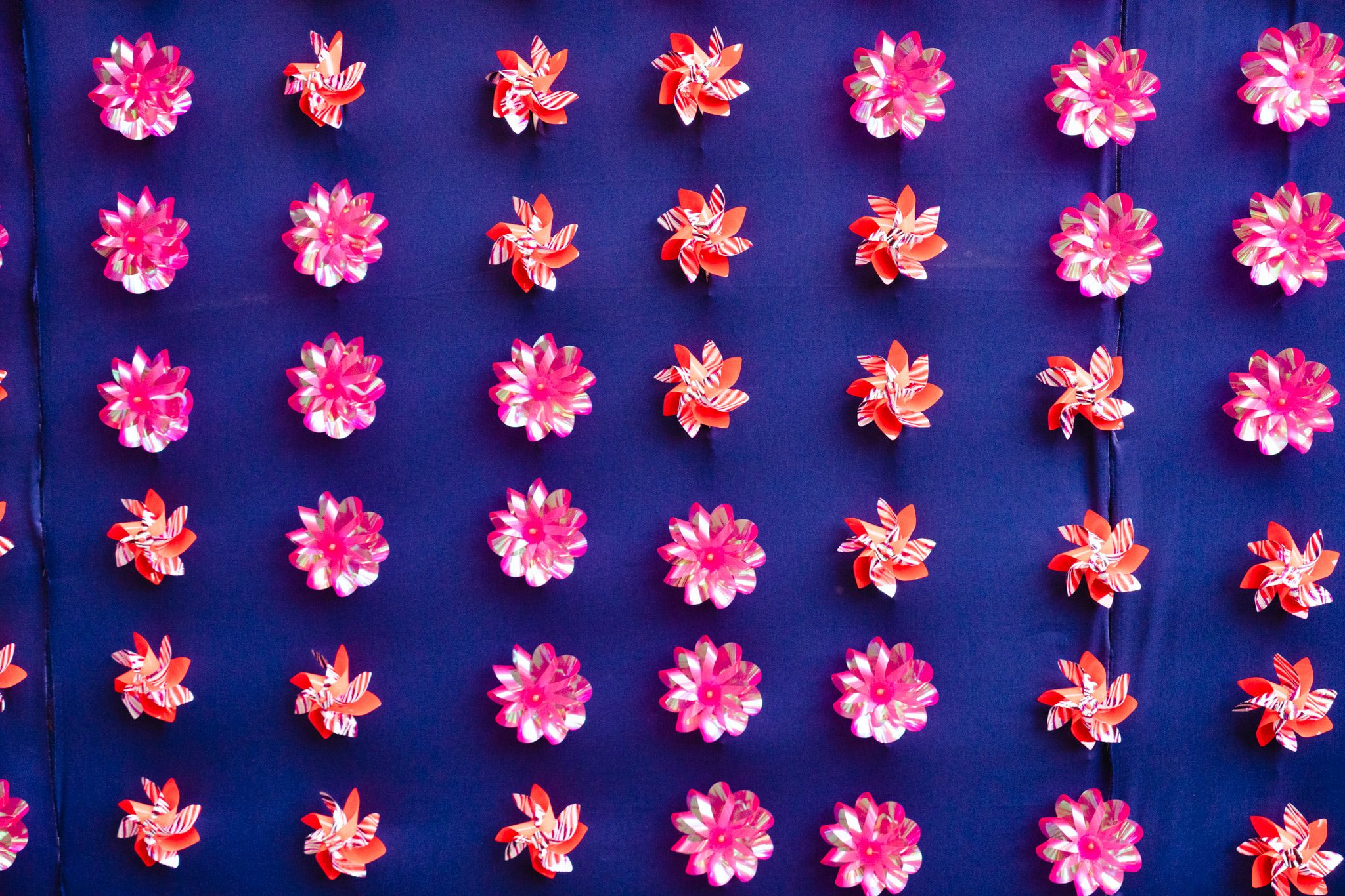 Colorful paper flowers arranged in grid on dark blue fabric