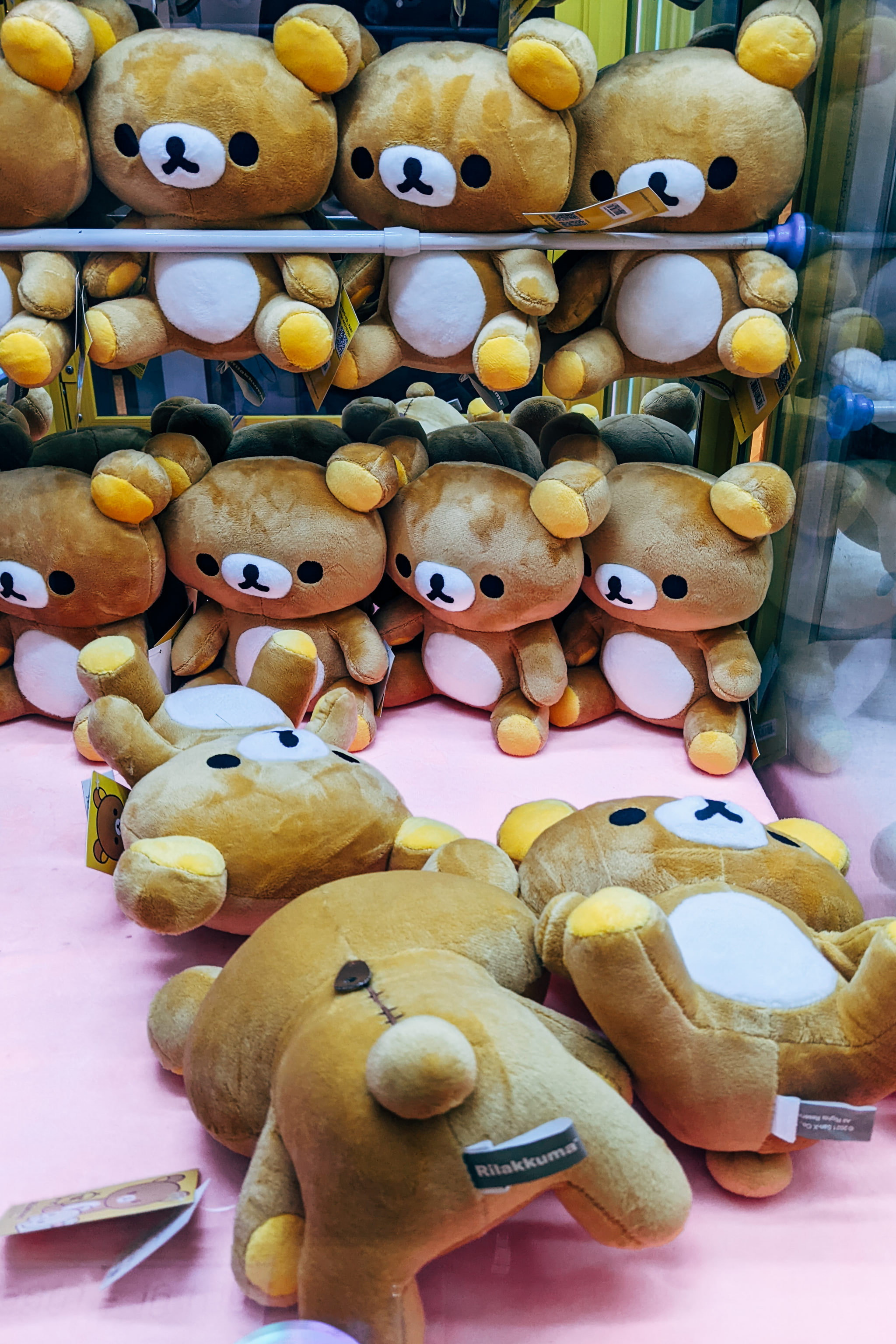 Multiple brown teddy bear plush toys inside a crane claw arcade machine.