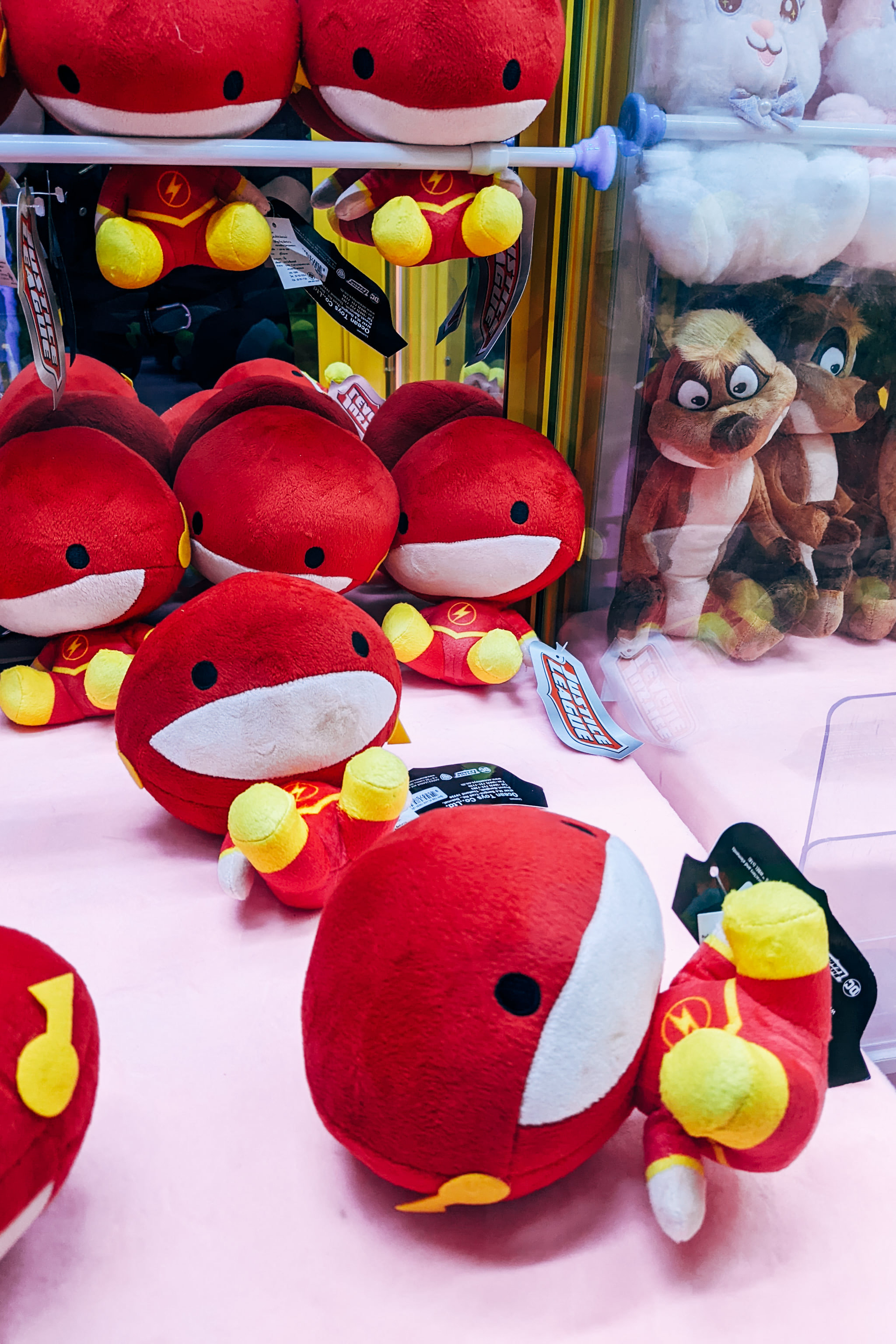 Row of red superhero plush toys inside an arcade claw machine
