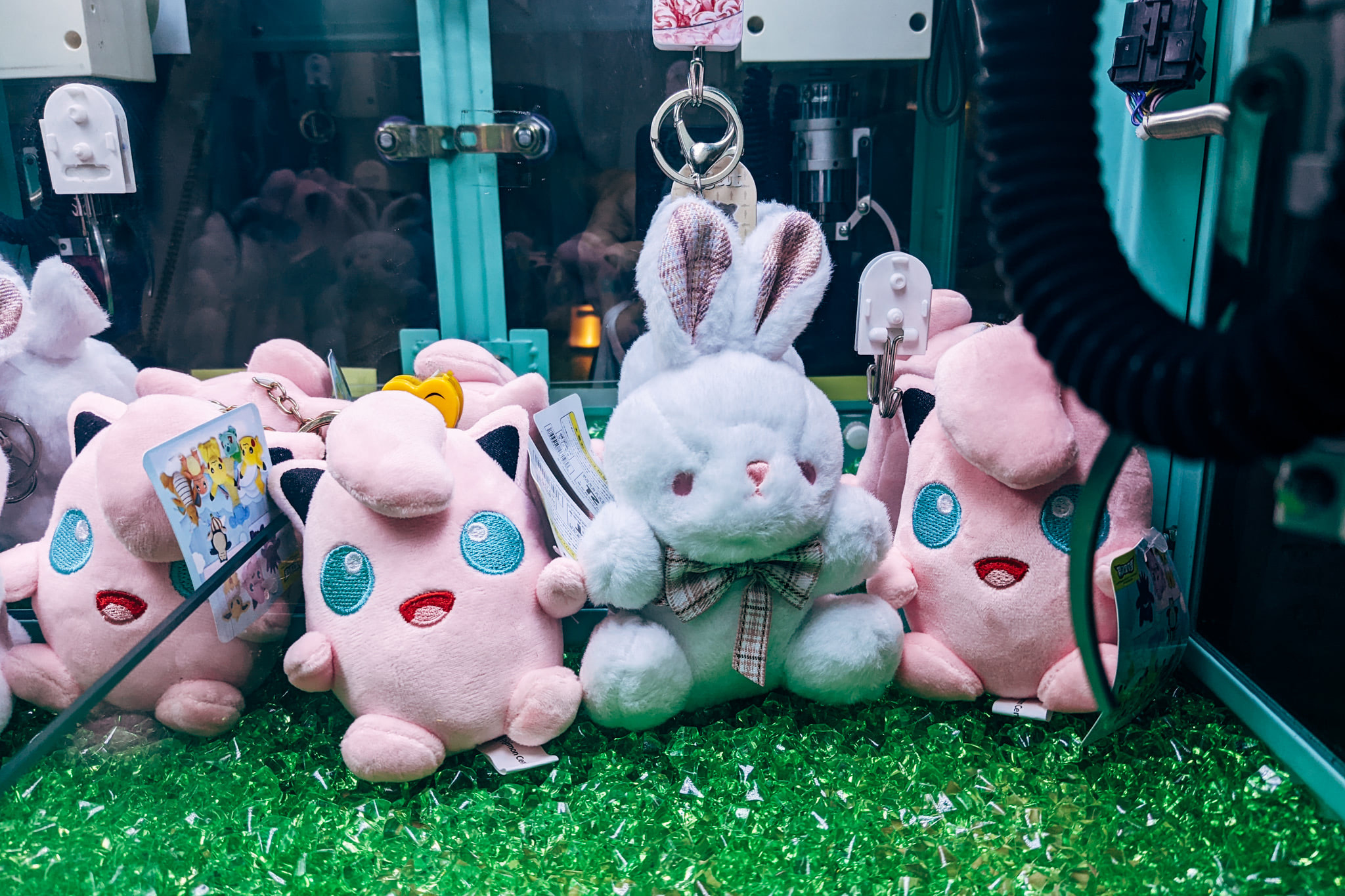 Plush toys including a white bunny and pink characters inside a claw machine arcade game