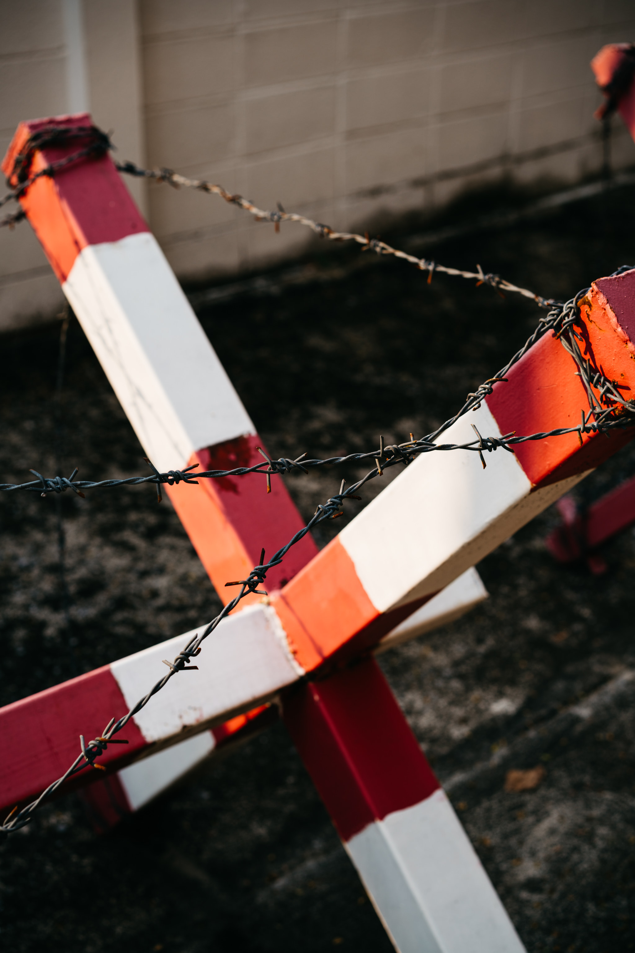 Red and white barrier with barbed wire in foreground