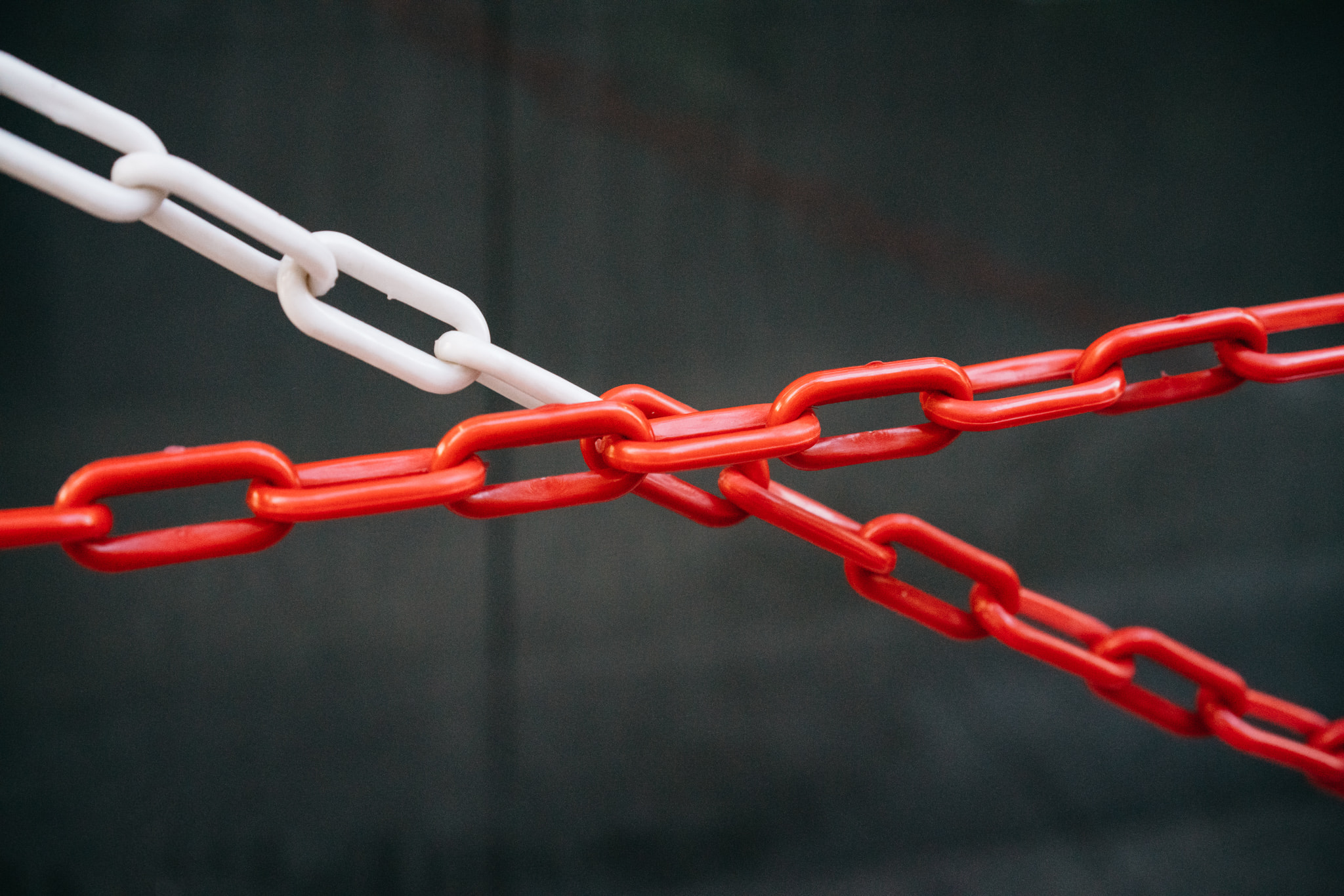 Red and white plastic chains linked together against a dark background