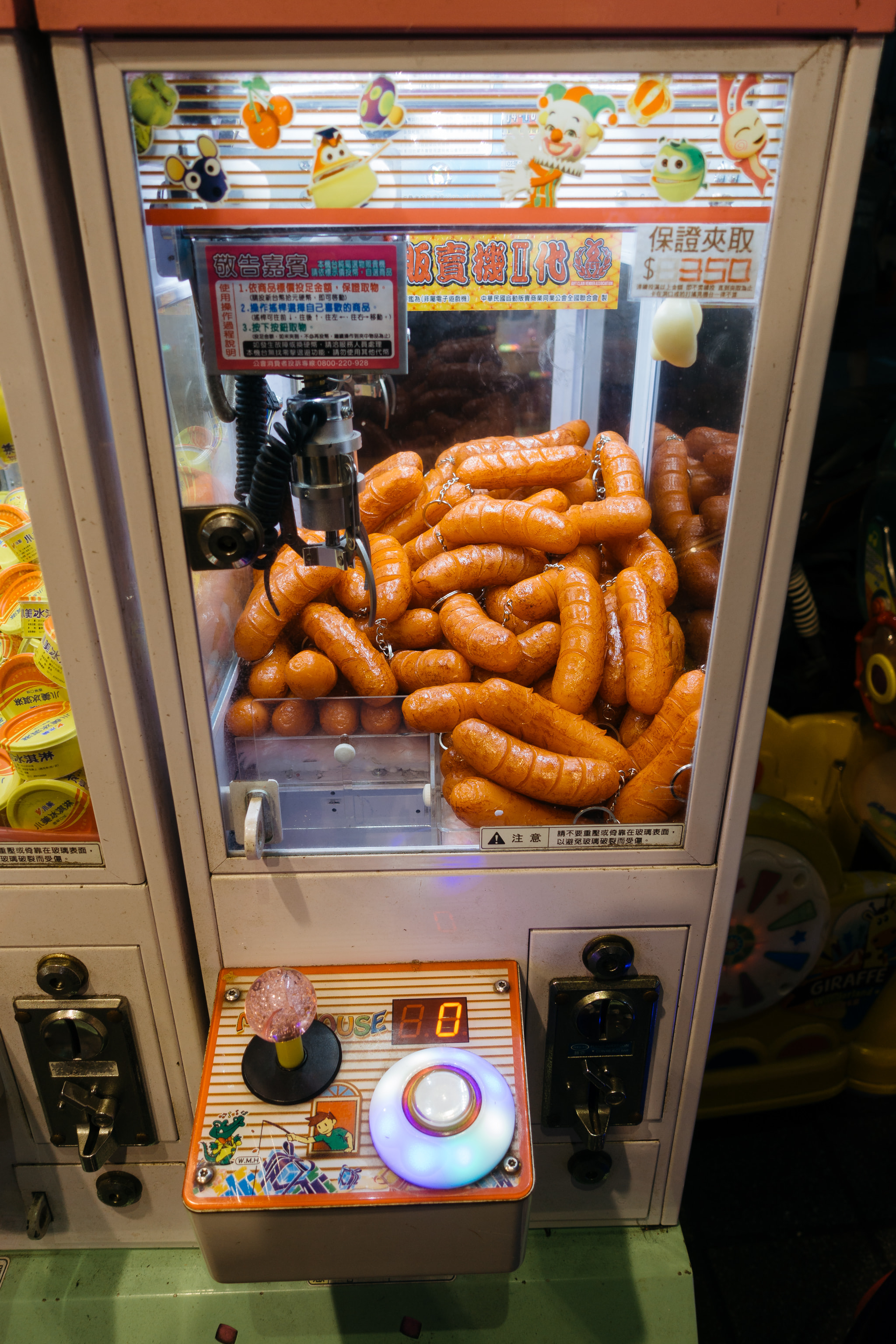 Claw machine filled with sausage keychains in an arcade